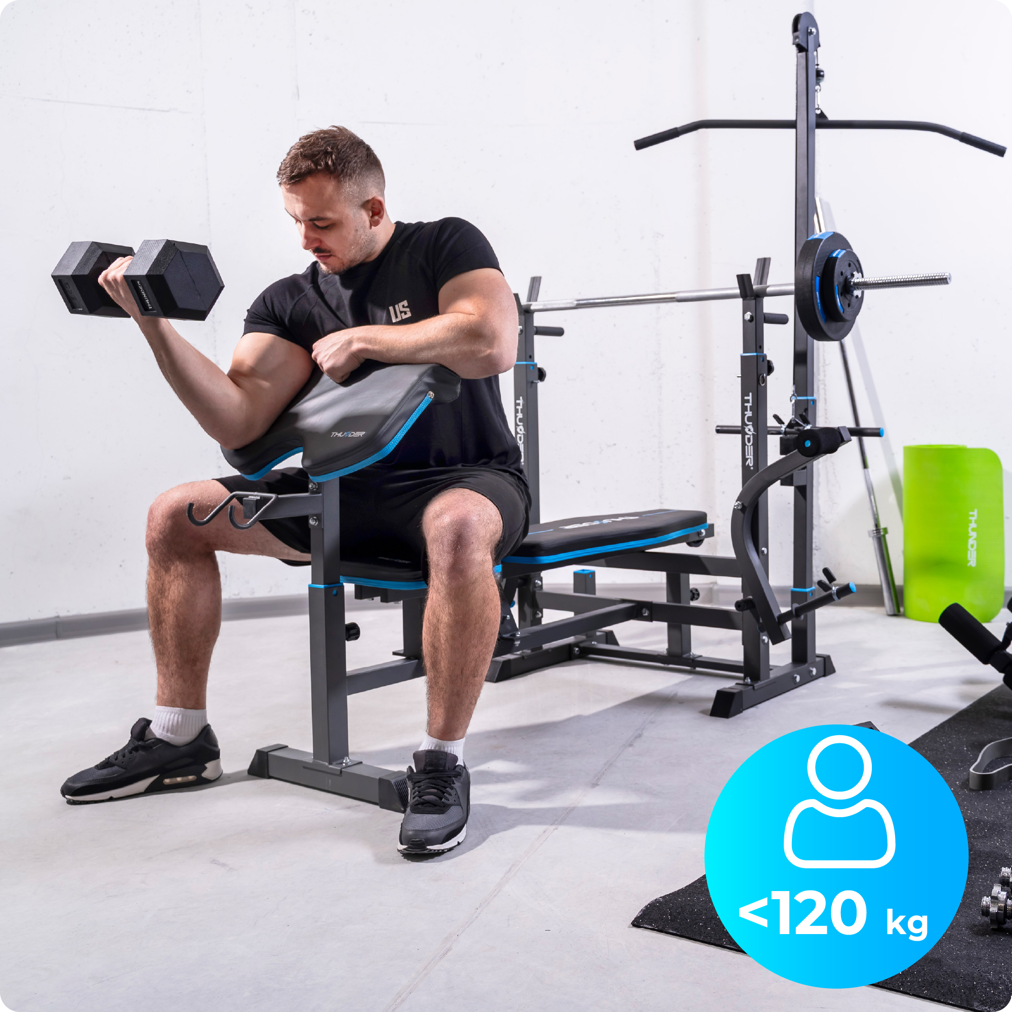 Mężczyzna wykonuje uginanie ramion na ławce do ćwiczeń. Hantle w prawej ręce. Ławka czarno-niebieska.