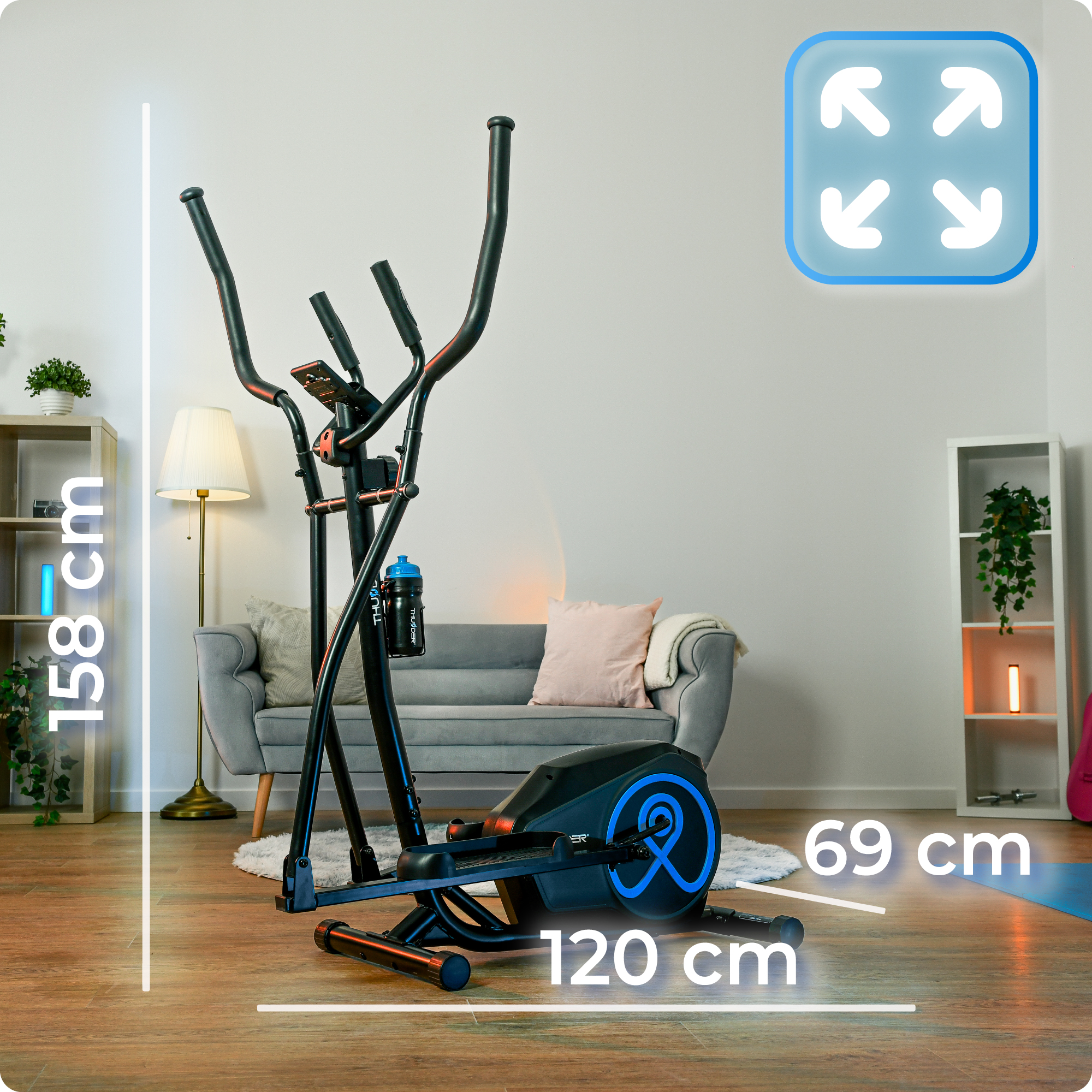 Czarna i niebieska maszyna eliptyczna w salonie, wymiary są wyświetlane. Wymiary to 158 cm x 120 cm x 69 cm.