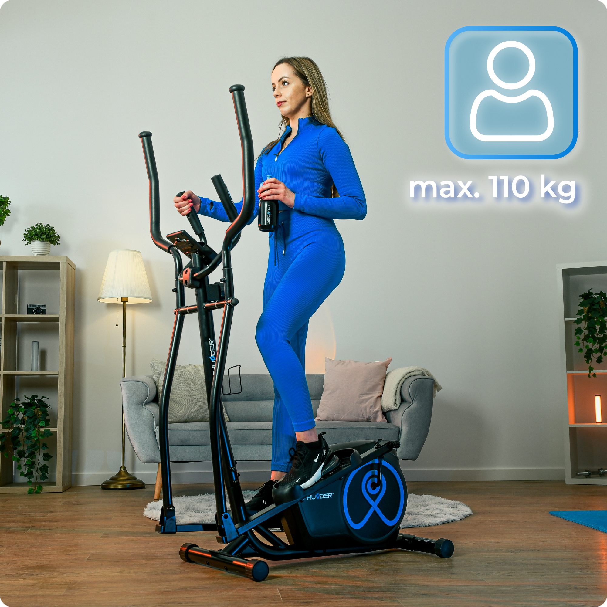Kobieta w niebieskim stroju do ćwiczeń korzystająca z maszyny eliptycznej. Wyświetla maksymalną wagę 110 kg. Trzyma butelkę z wodą.