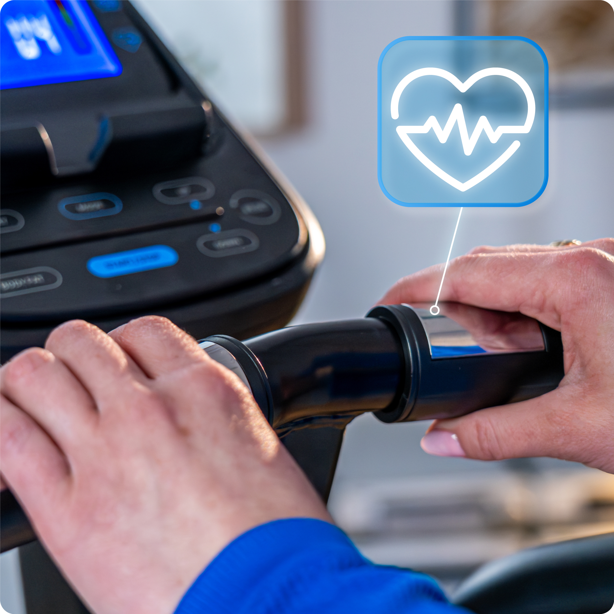 Ręce osoby trzymające uchwyty orbitreka. Na ekranie wyświetlana jest ikona tętna.