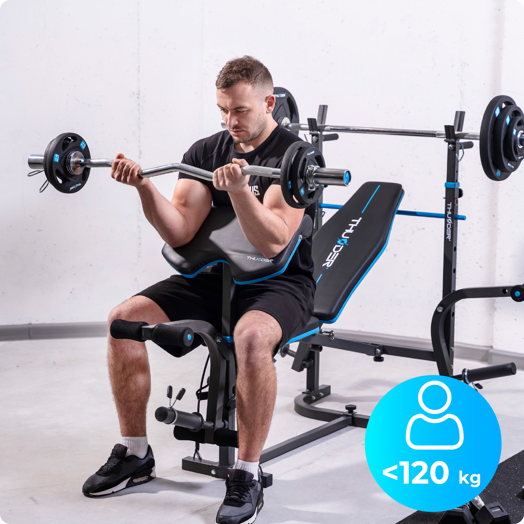 Mężczyzna używa ławki do ćwiczeń i podnosi sztangę. Znak wskazuje maksymalną wagę 120 kg.