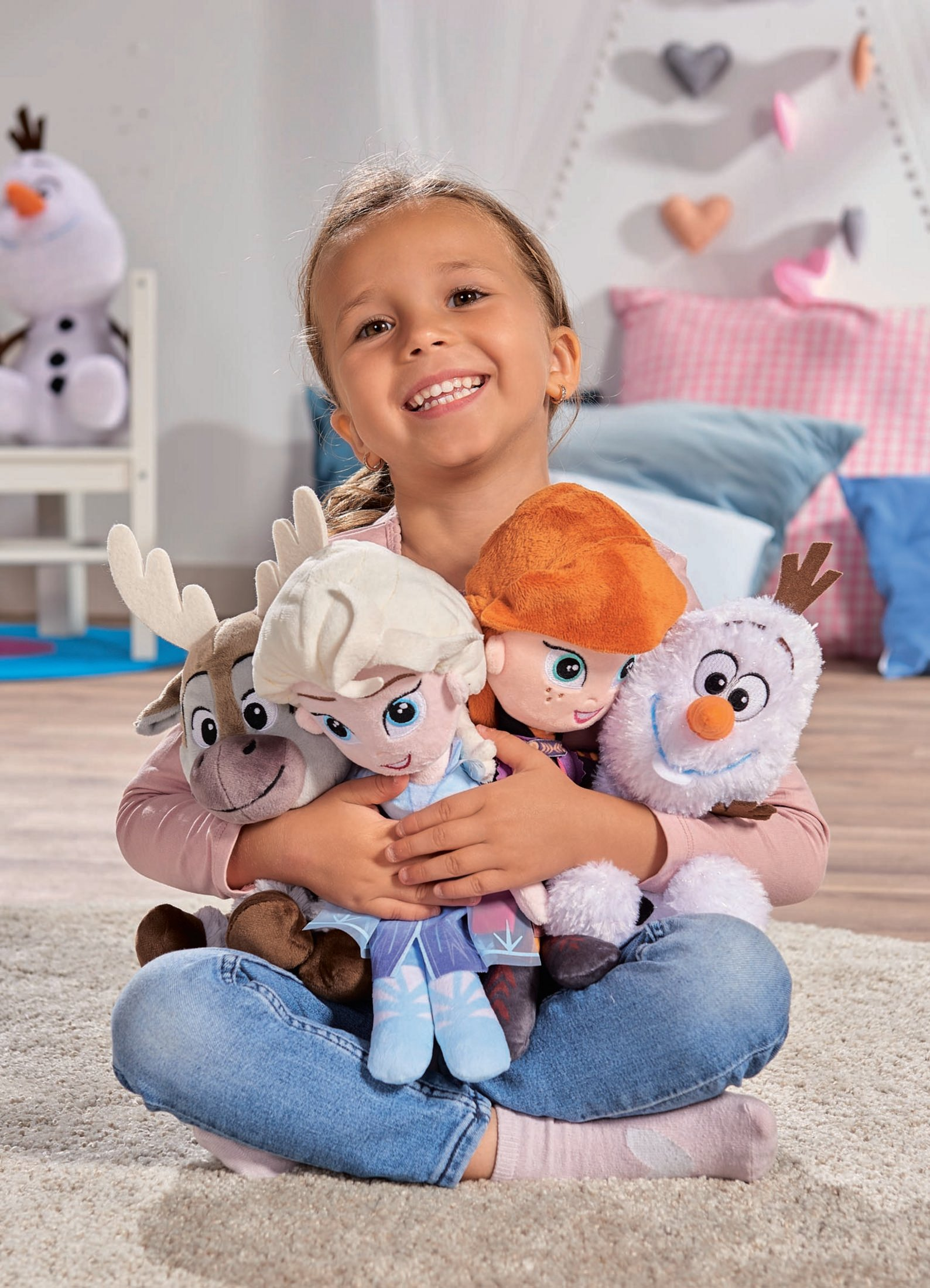 Ein Mädchen hält Frozen-Puppen: Anna, Elsa, Olaf und Sven, lächelt in die Kamera.