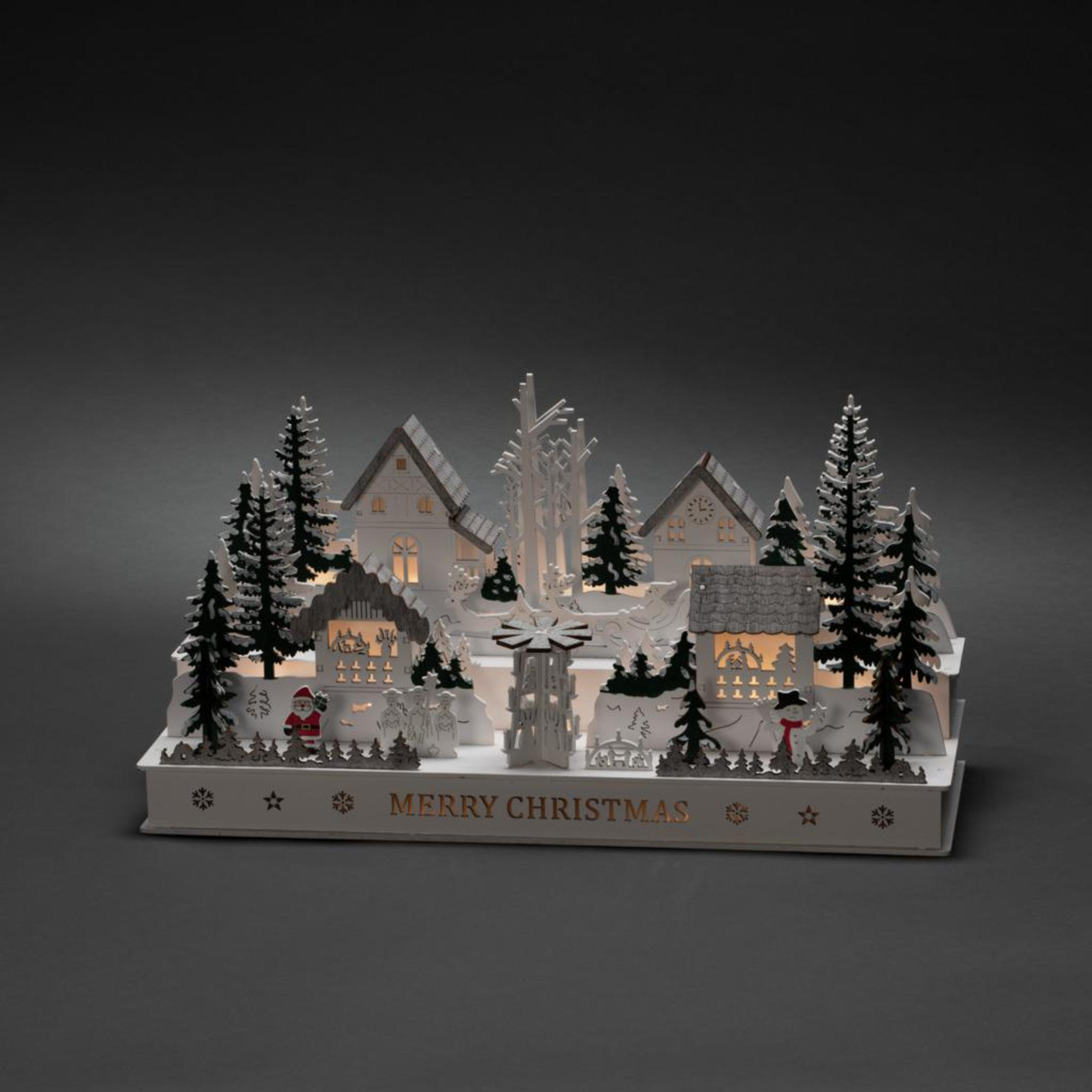 Weihnachtsdorf-Szene mit beleuchteten Häusern, Bäumen und Figuren vor dunklem Hintergrund.