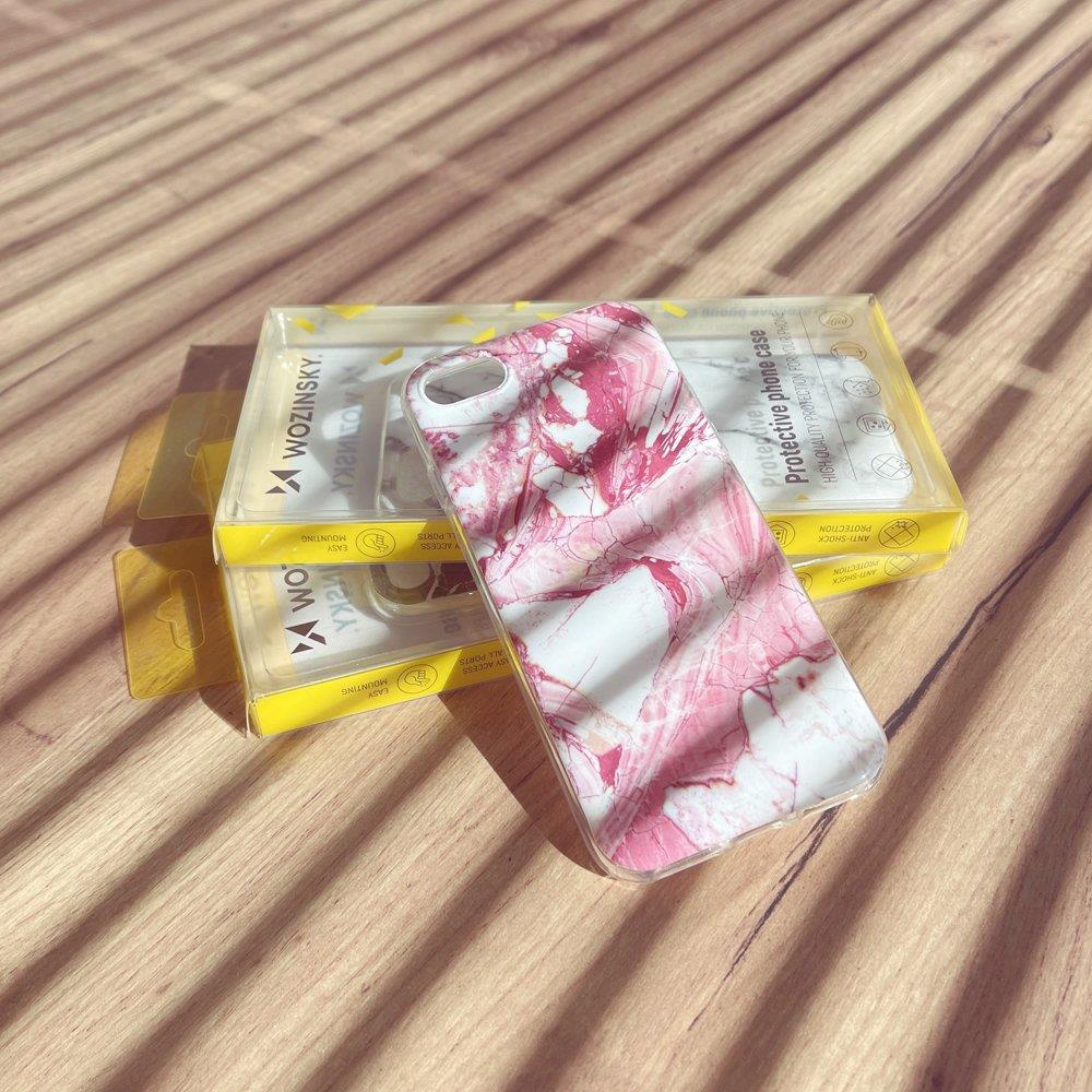 Etui na telefon z różowym marmurem na drewnianym stole z pudełkami.