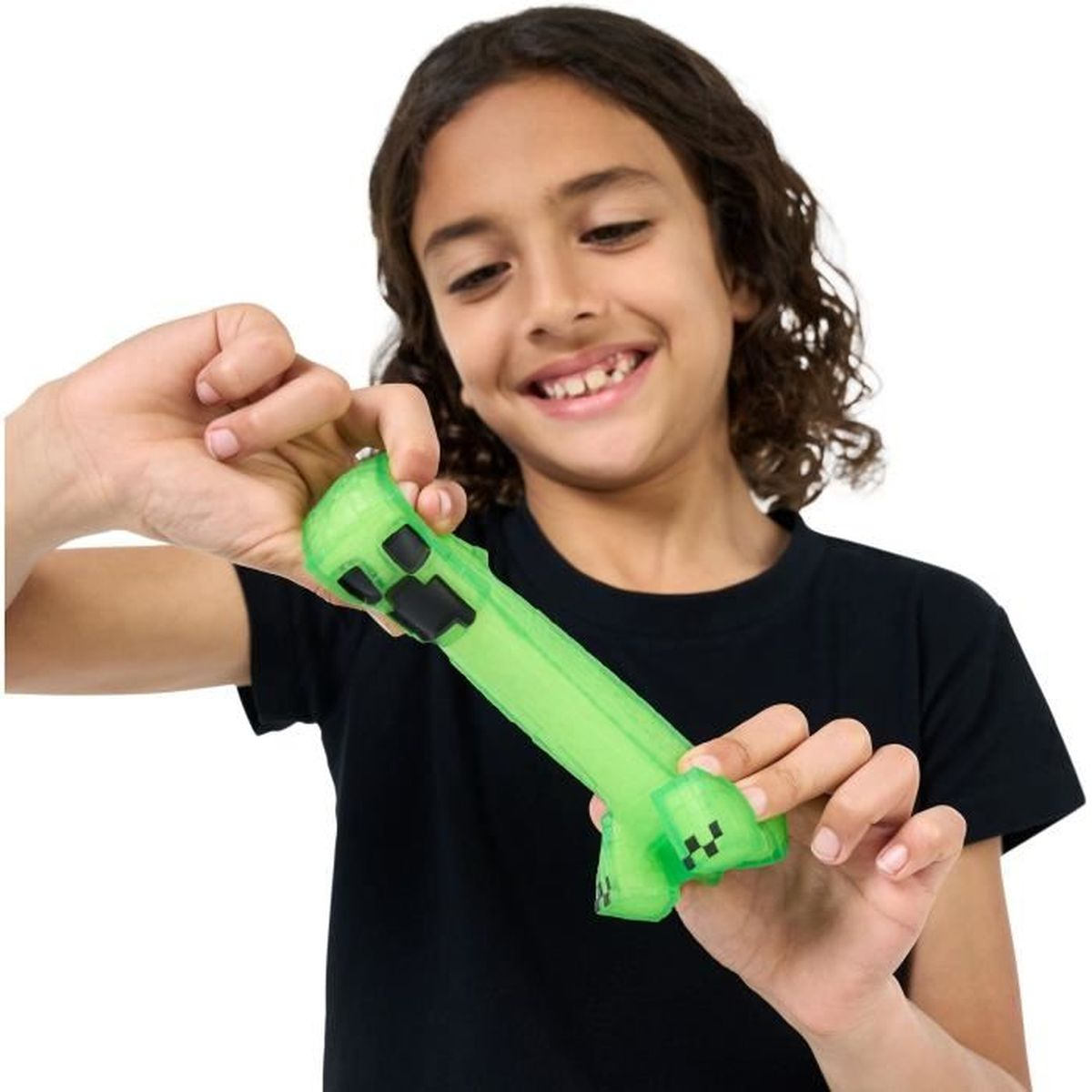 Un niño pequeño sonriendo sosteniendo un juguete Creeper de Minecraft verde. El juguete es verde y en bloques.