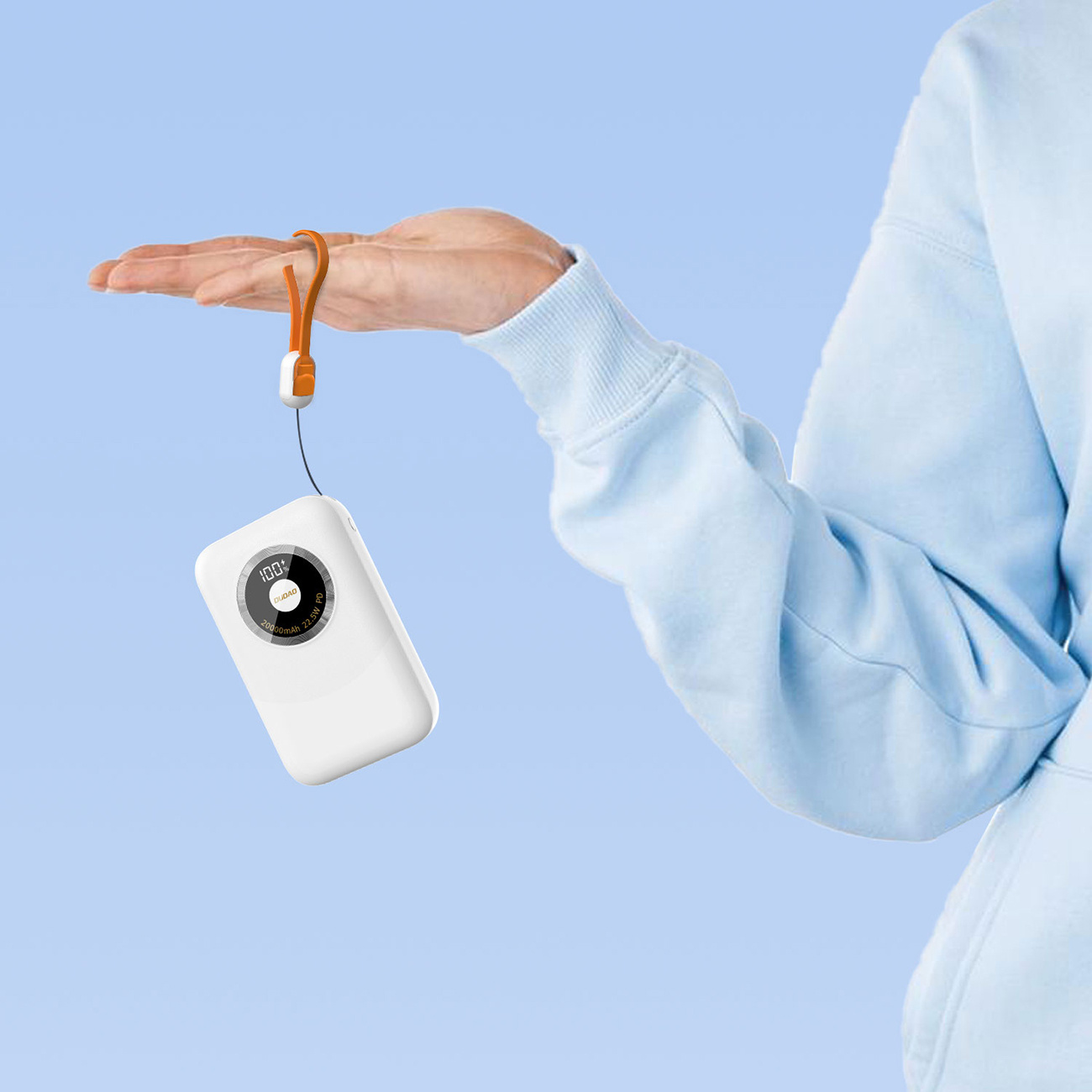 Dłoń trzymająca biały power bank. Power bank ma pomarańczowy pasek.