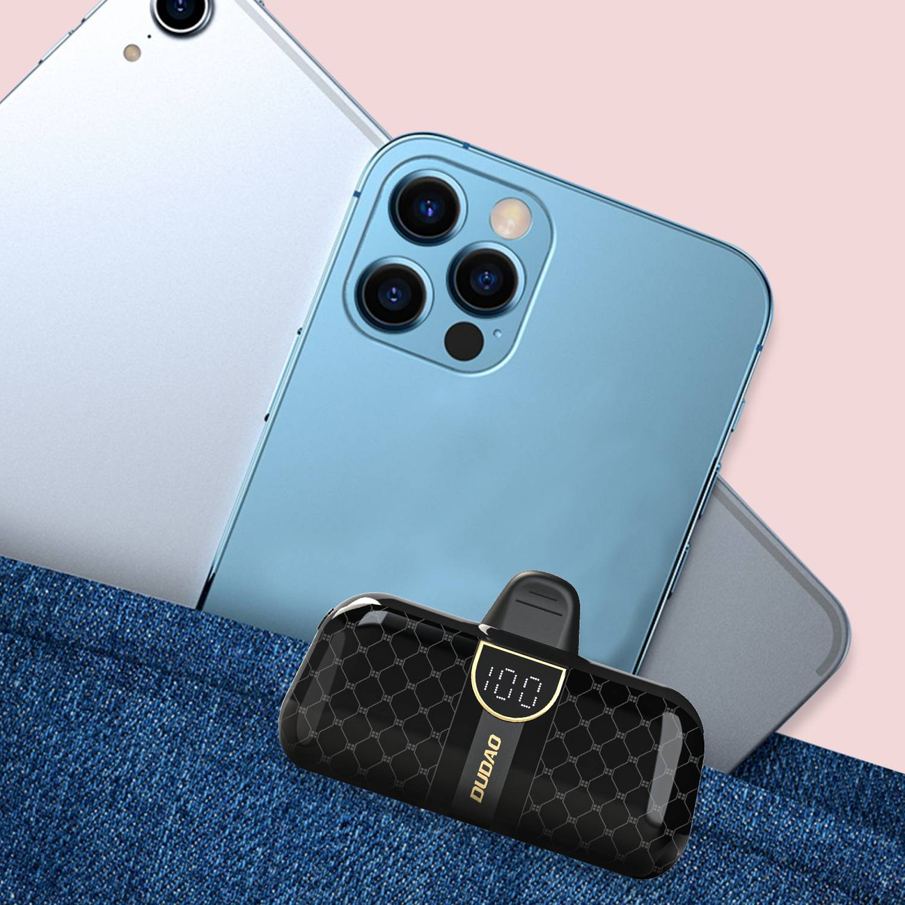 Czarny power bank z cyfrowym wyświetlaczem leży na powierzchni dżinsu, obok telefonów.