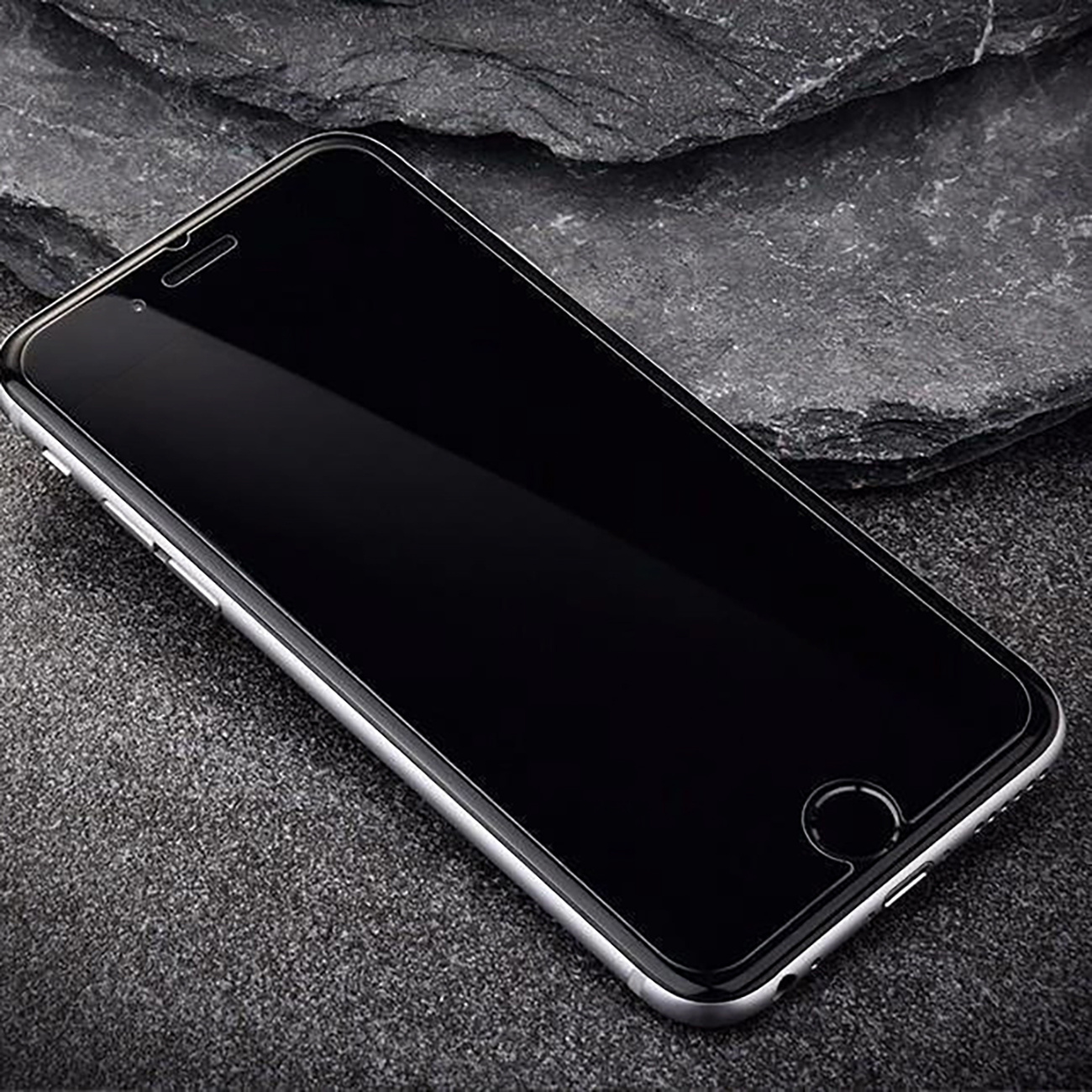 Smartfon z czarną ochroną ekranu na ciemnoszarej powierzchni. Telefon jest lekko przechylony.