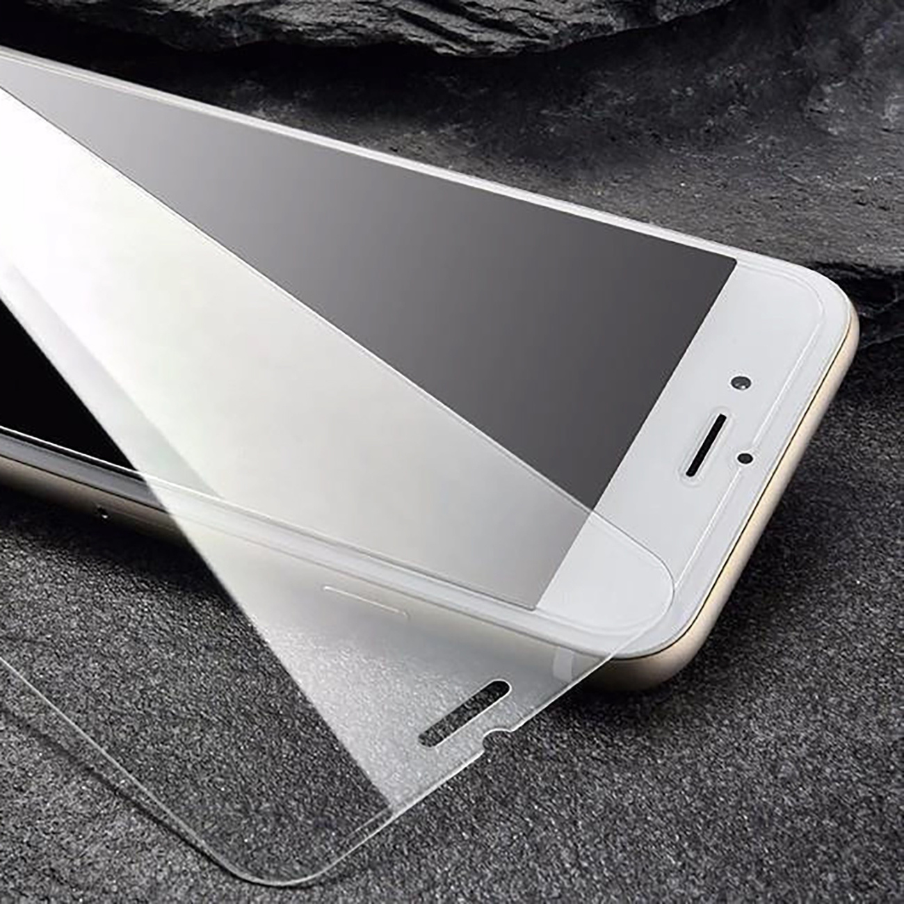 Telefon, do którego jest nakładany ochraniacz ekranu. Znajduje się na ciemnej, teksturowanej powierzchni.