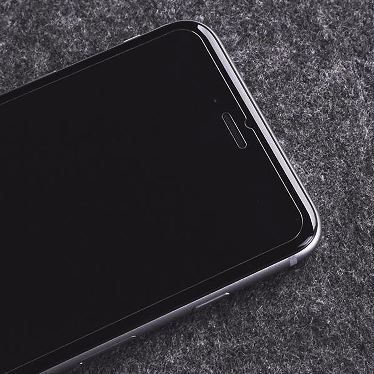 Zbliżenie ekranu telefonu pokazujące przód smartfona na szarej powierzchni.