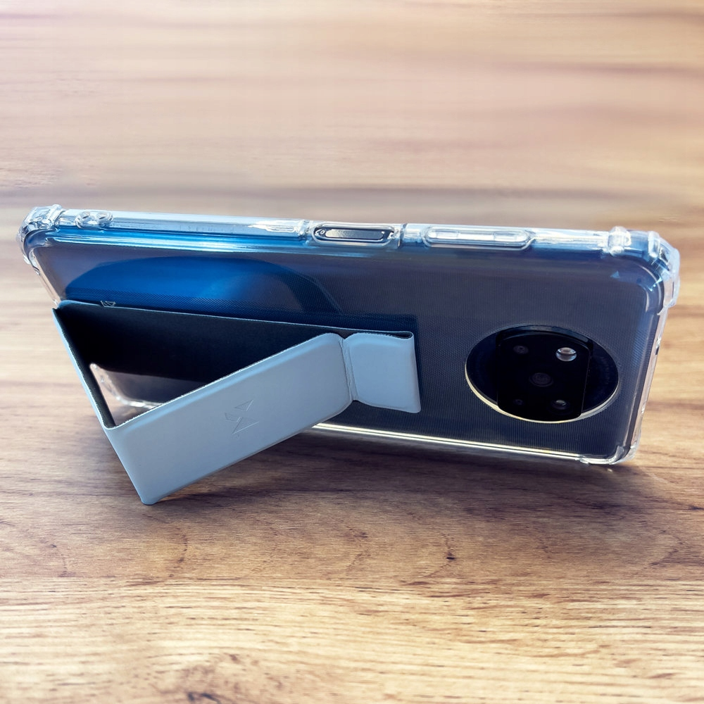 Telefon na drewnianym stole, podniesiony przez podstawkę.  Przezroczyste etui chroni telefon, pokazując jego tył.