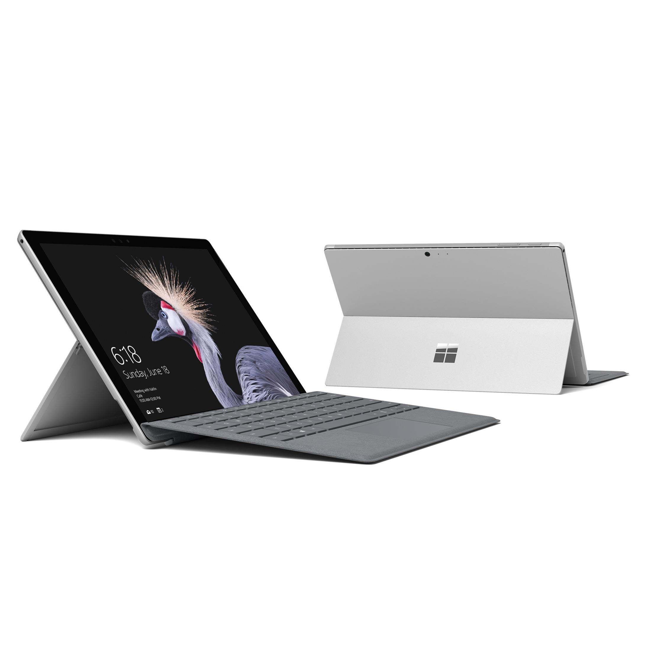 Zwei silberne Microsoft Surface Tablets. Eines geöffnet mit Tastatur, zeigt Uhrzeit.