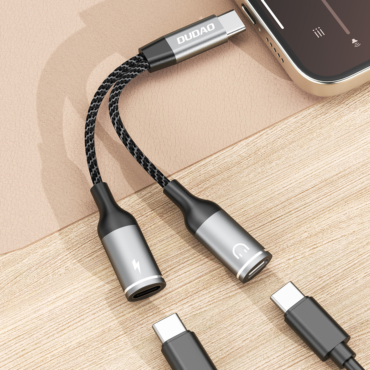 Srebrny i czarny adapter USB-C na 3,5 mm audio. Czarny pleciony kabel. Telefon i złącze USB-C.