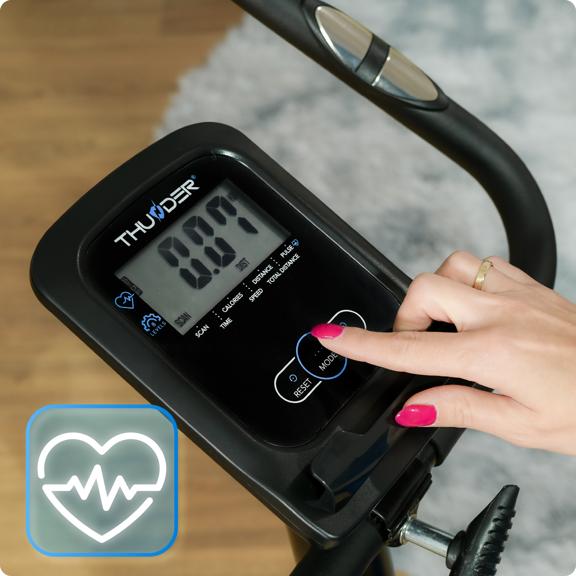 Dłoń kobiety naciskająca przycisk na wyświetlaczu roweru stacjonarnego. Ikona tętna widoczna.