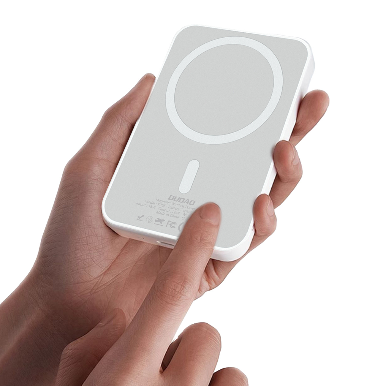 Ręka osoby trzymająca biały i szary magnetyczny power bank z okrągłym obszarem ładowania.