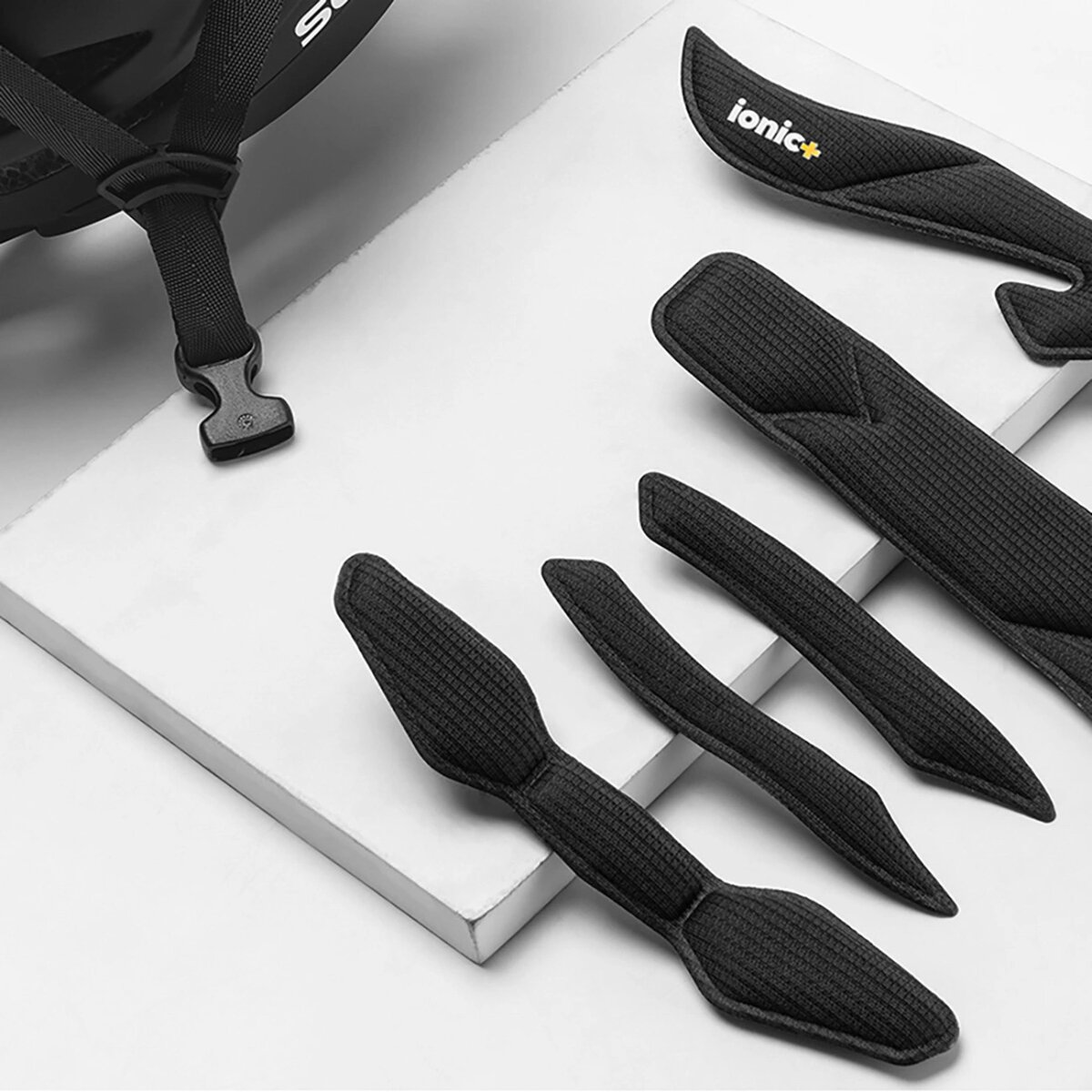 Wkładki do kasku. Czarne wkładki i paski znajdują się na białej powierzchni.