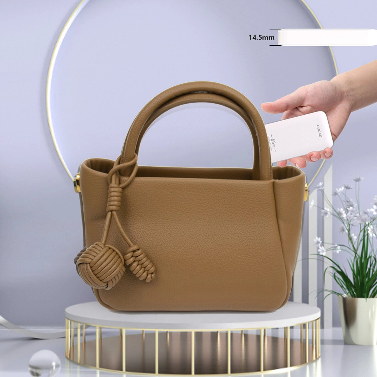 Torebka z małym portfelem obok, na stojaku. Torebka jest brązowa.