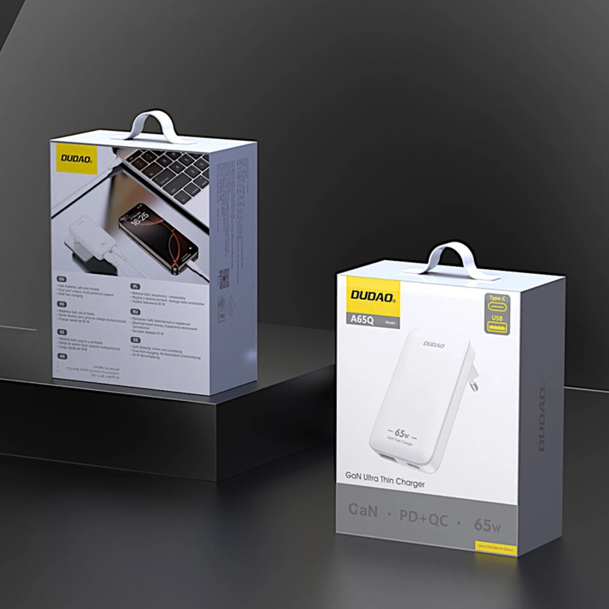 Dwa białe pudełka z ładowarką DUDAD. Jedno pokazuje ładujący się telefon. Pudełka mają uchwyty.