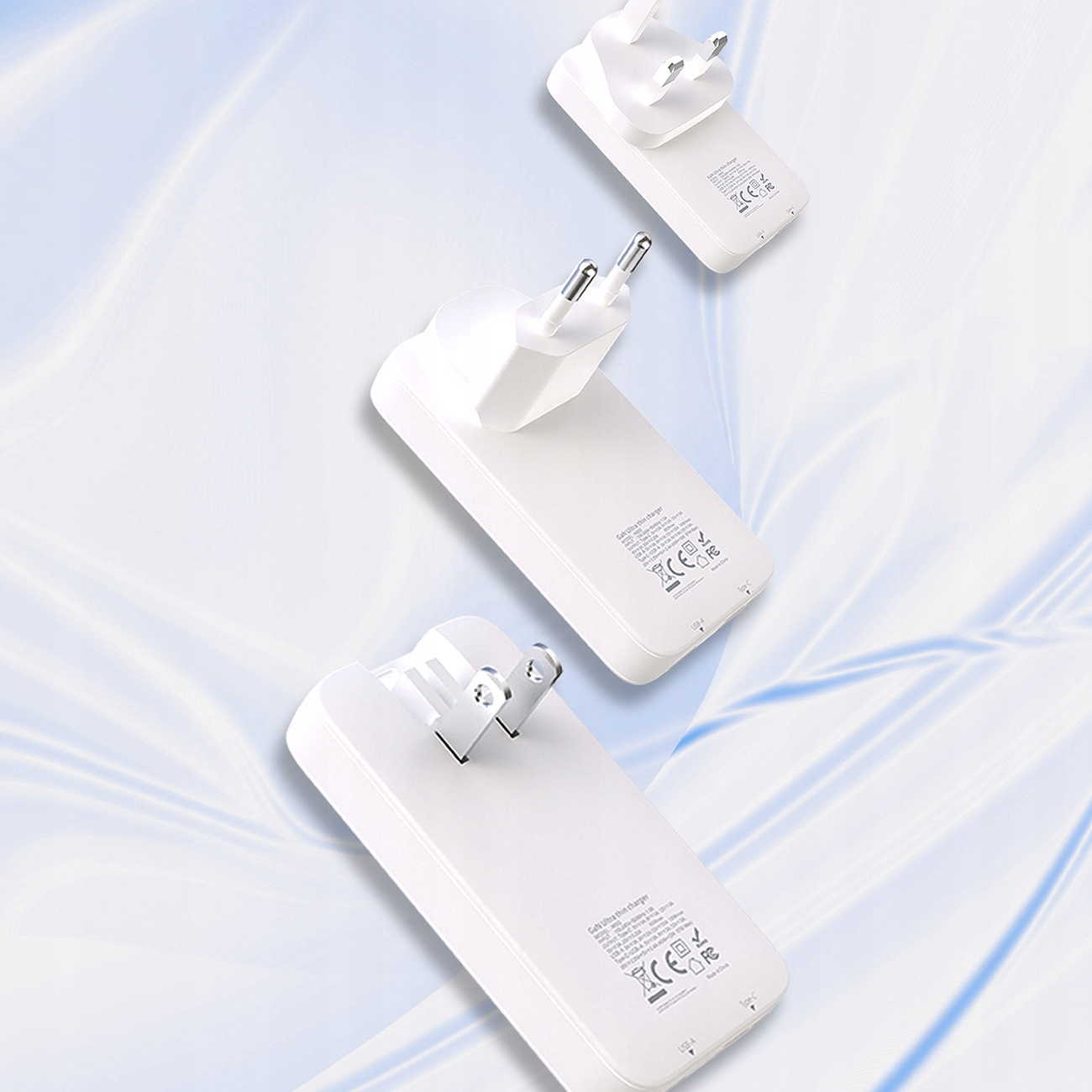 Trzy białe ładowarki z wtyczkami. Są pod kątem. Tło to niebieski wzór fal.
