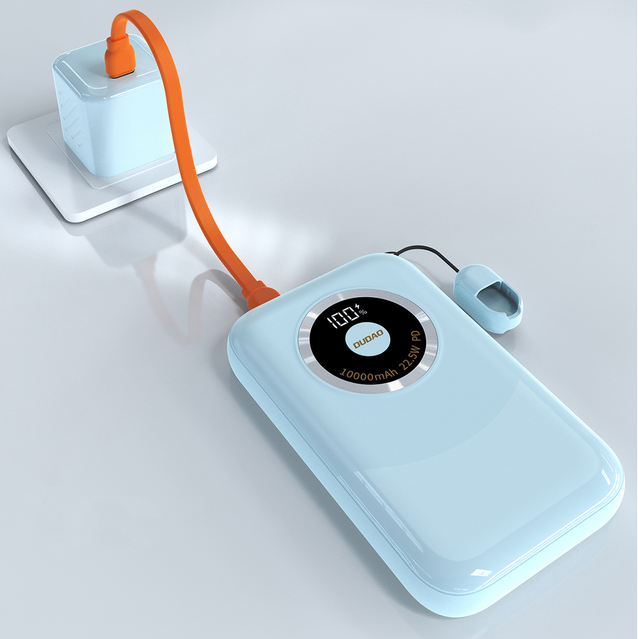 Niebieski power bank w trakcie ładowania. Ma pomarańczowy kabel podłączony do ładowarki ściennej.