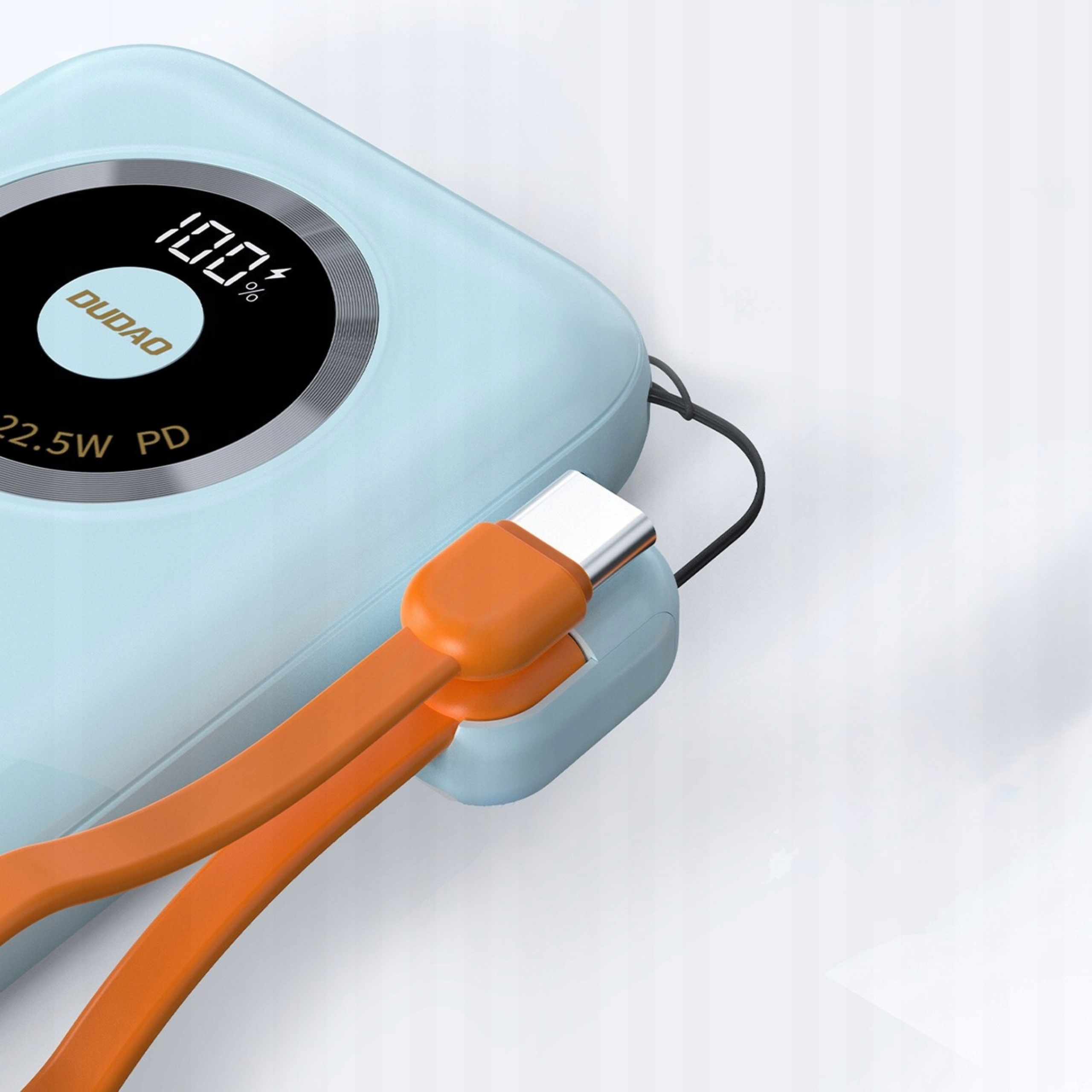 Niebieska ładowarka z pomarańczowymi kablami. Ładowarka pokazuje 100% oraz napisy DUDO i 22,5W PD.