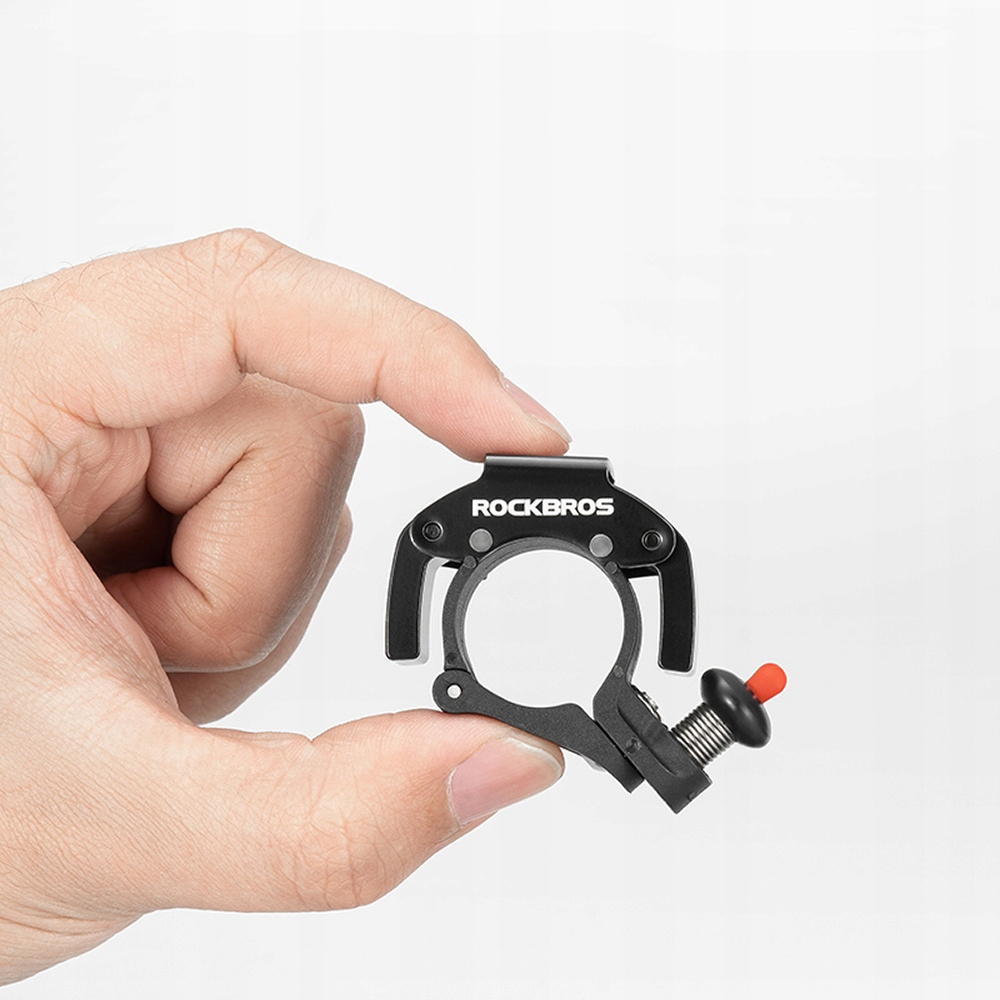 Ręka trzyma czarny uchwyt do lampki rowerowej ROCKBROS. Posiada czerwony przycisk i śrubę.