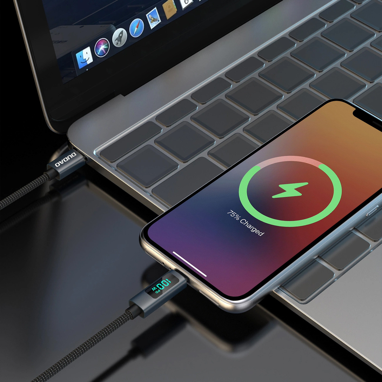 Telefon ładujący się przez kabel, pokazujący '75% naładowania' i '100W' na wyświetlaczu kabla. Widoczny laptop.