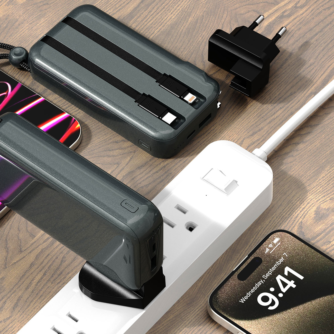 Power bank i telefony na drewnianym stole, podłączone do listwy zasilającej. Jeden pokazuje godzinę 9:41.