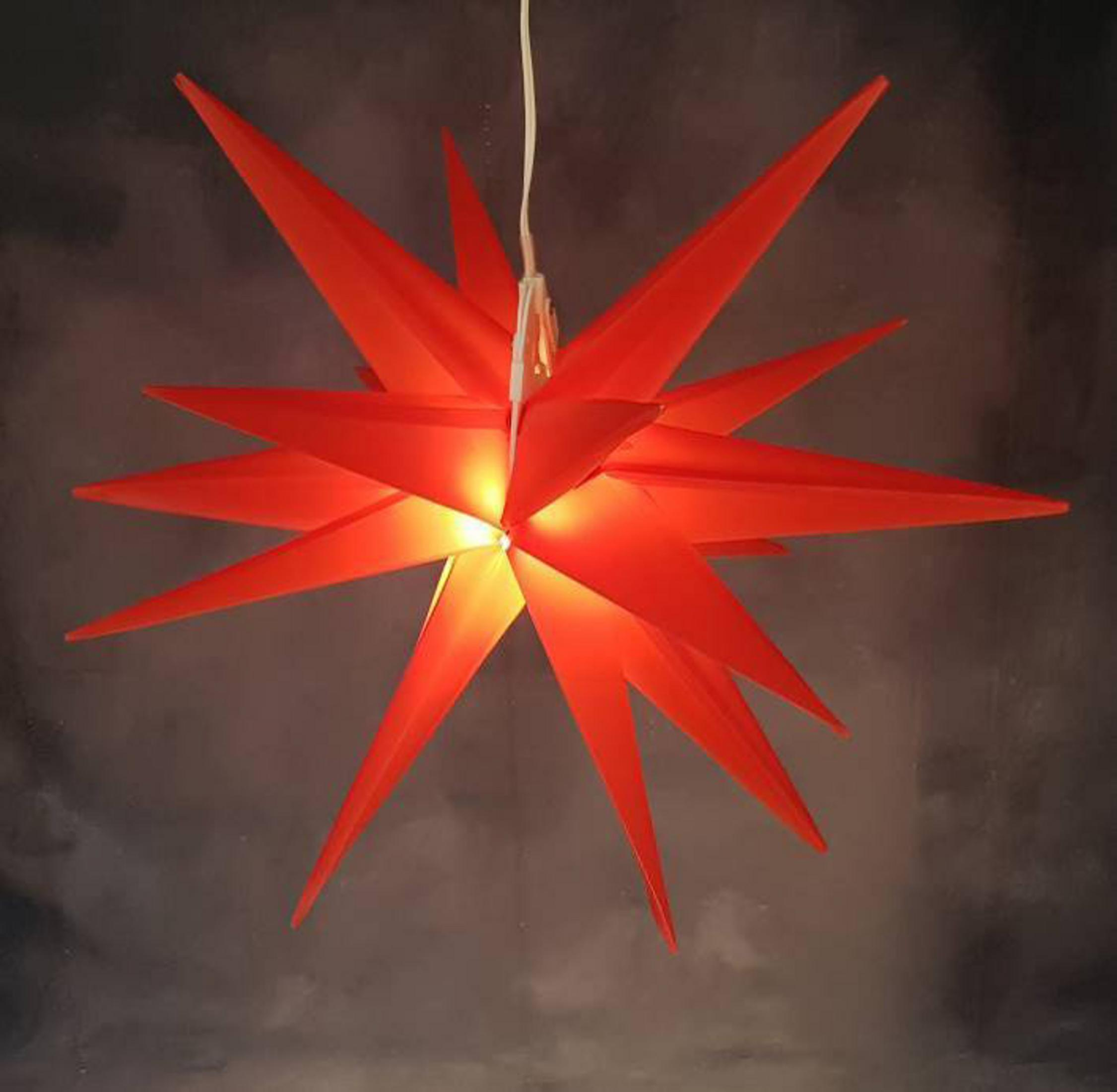 Roter sternförmiger Weihnachtsschmuck. Warmes Licht scheint von innen.