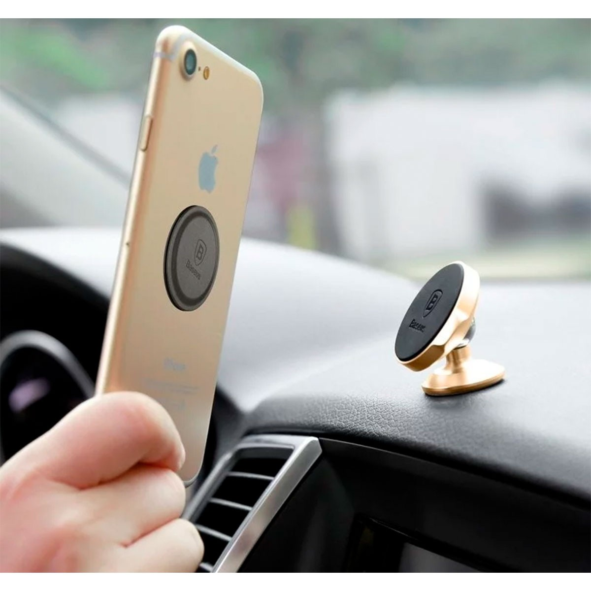 Ręka trzymająca złotego iPhone'a z magnetycznym uchwytem Baseus. Złoty uchwyt Baseus na desce rozdzielczej.