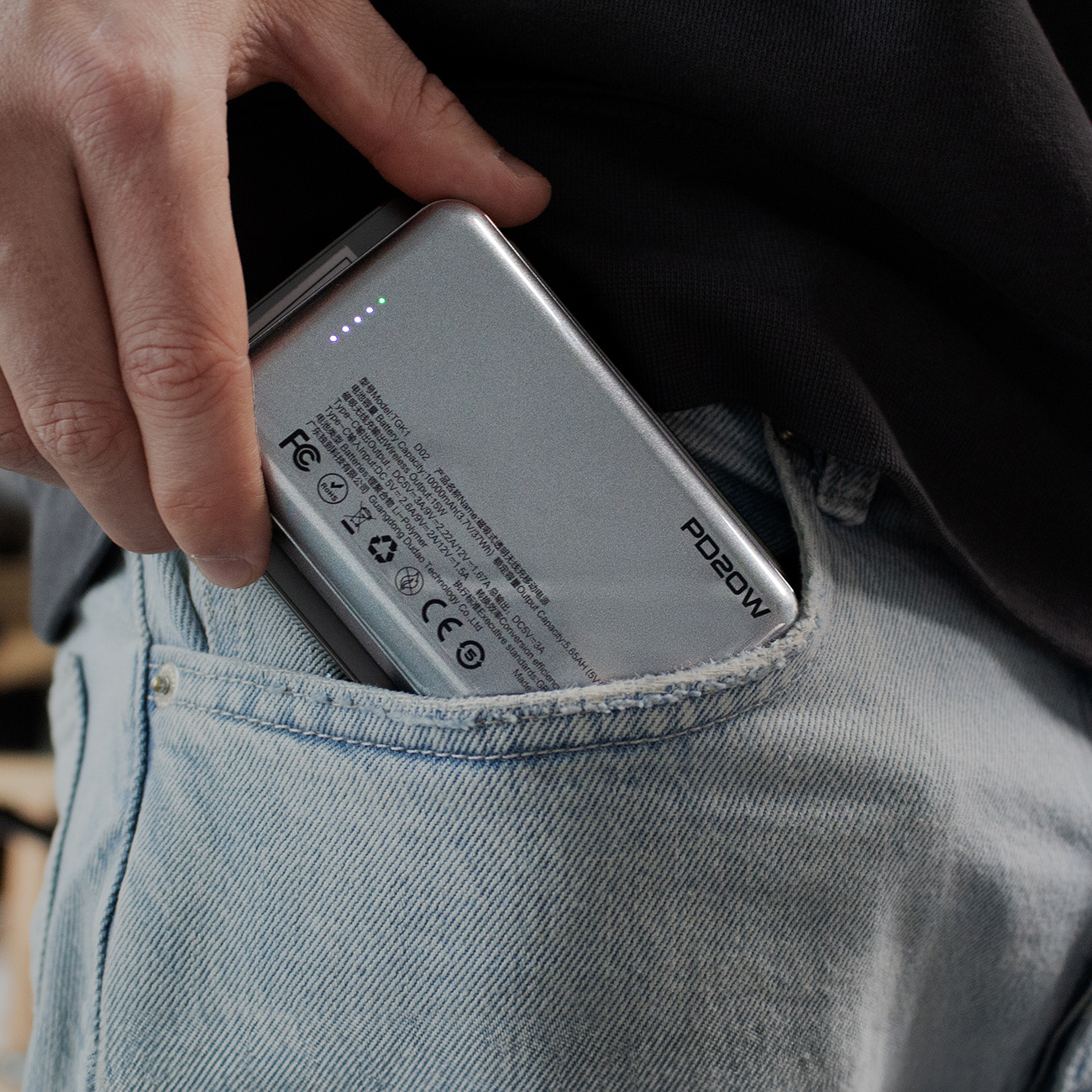 Osoba wkładająca power bank do kieszeni dżinsów.