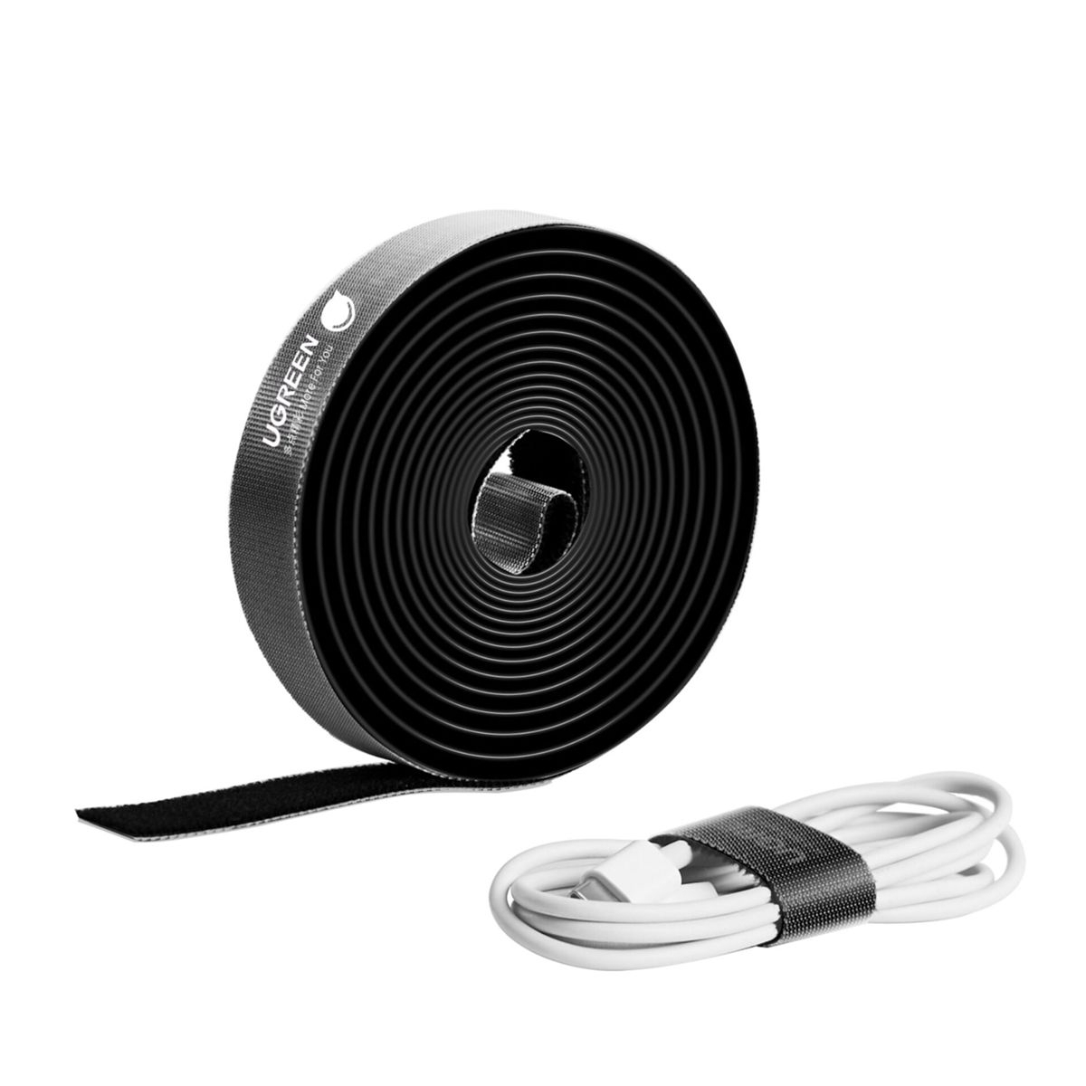 Czarny zwój organizera kabli UGREEN obok kabla związanego organizerem, białe tło.