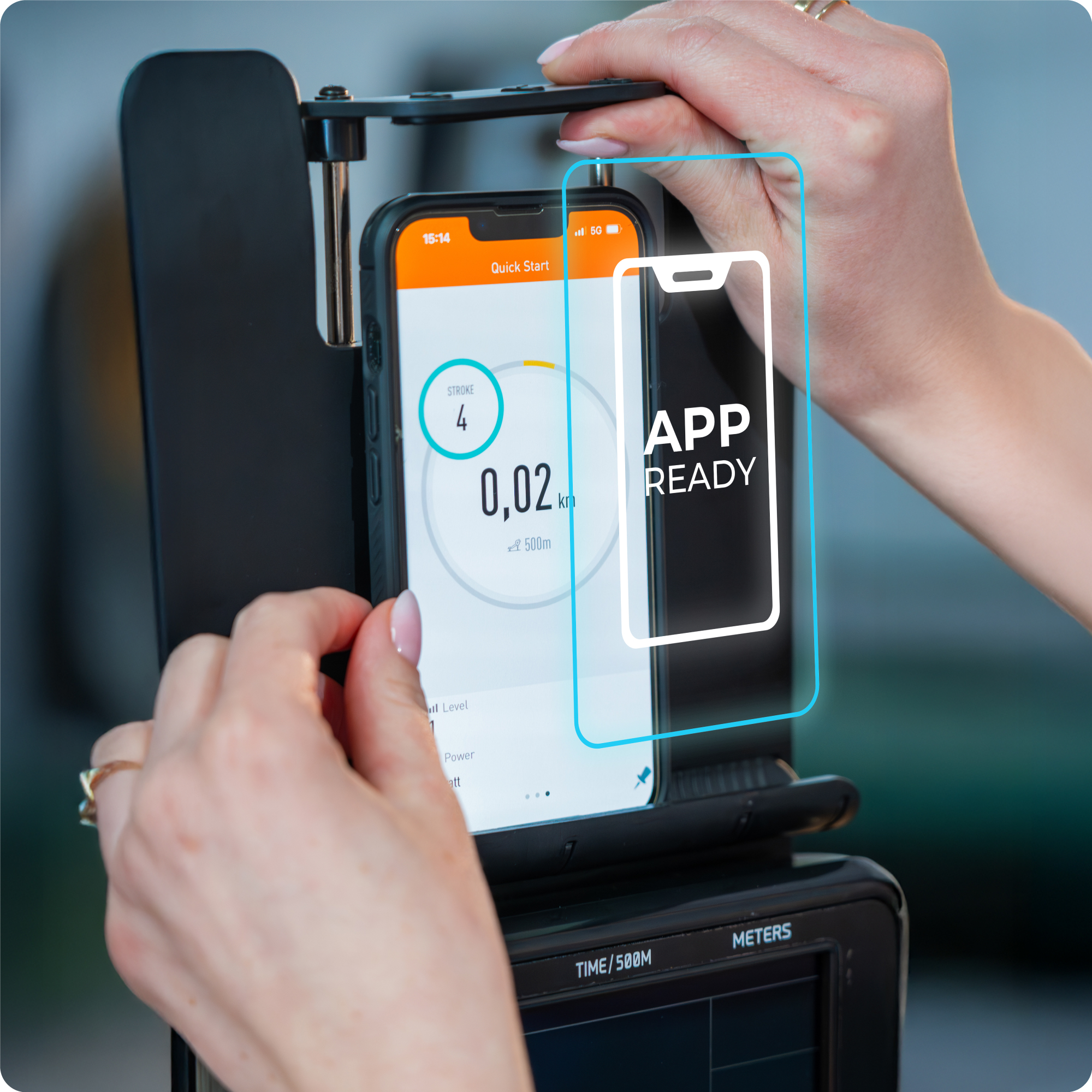 Ręce trzymają smartfon na stojaku. Ekran wyświetla 'APP READY'.