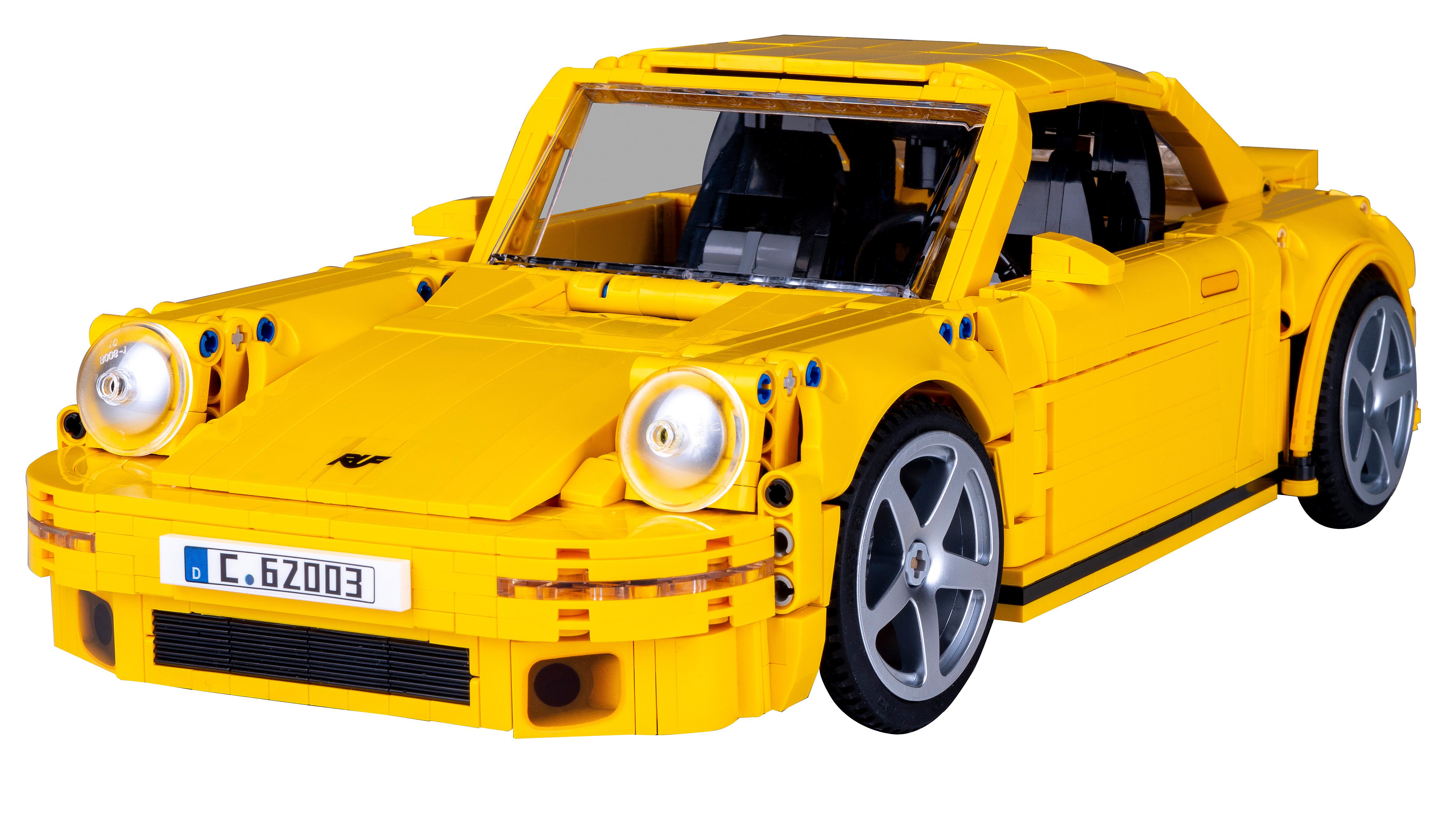 Augenhöhe-Aufnahme eines gelben Spielzeugautos vor einem weißen Hintergrund.