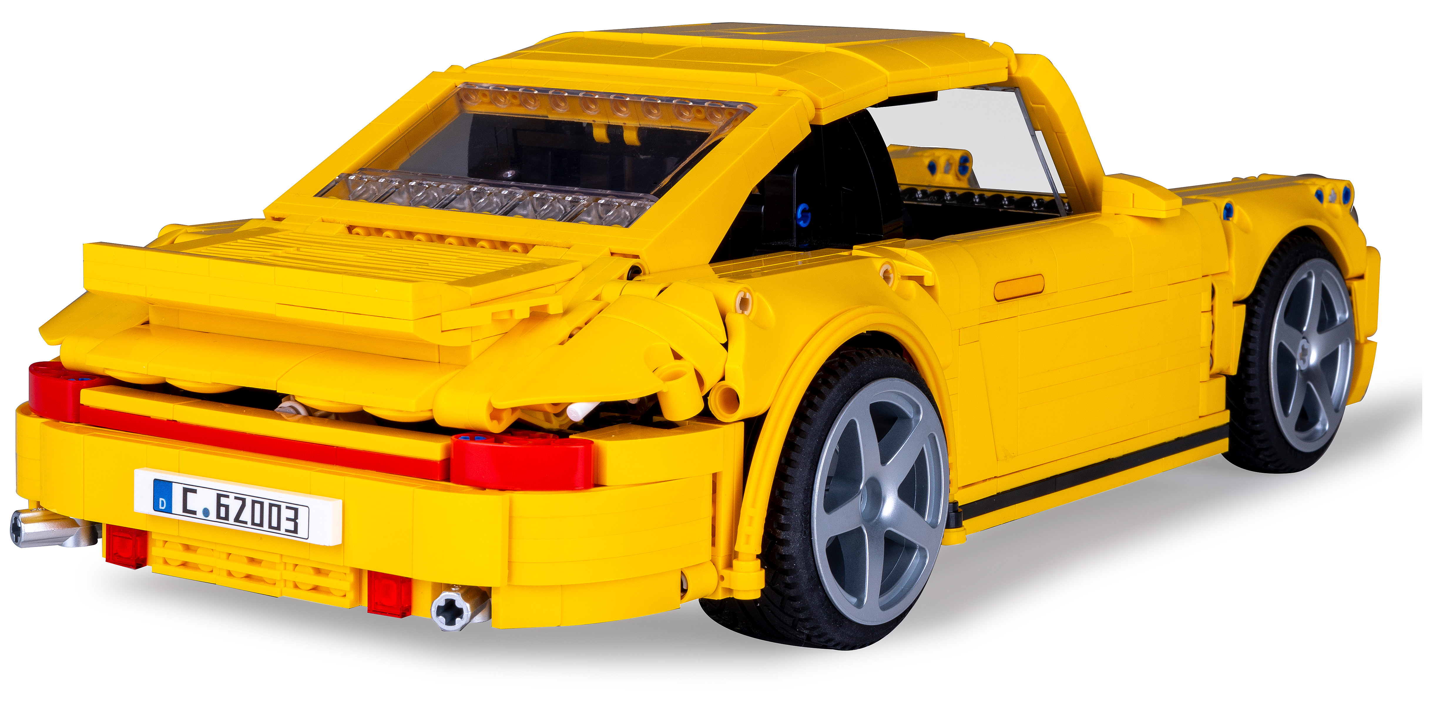 Die Rückseite eines gelben Spielzeugautos, auf Augenhöhe vor einem weißen Hintergrund aufgenommen.