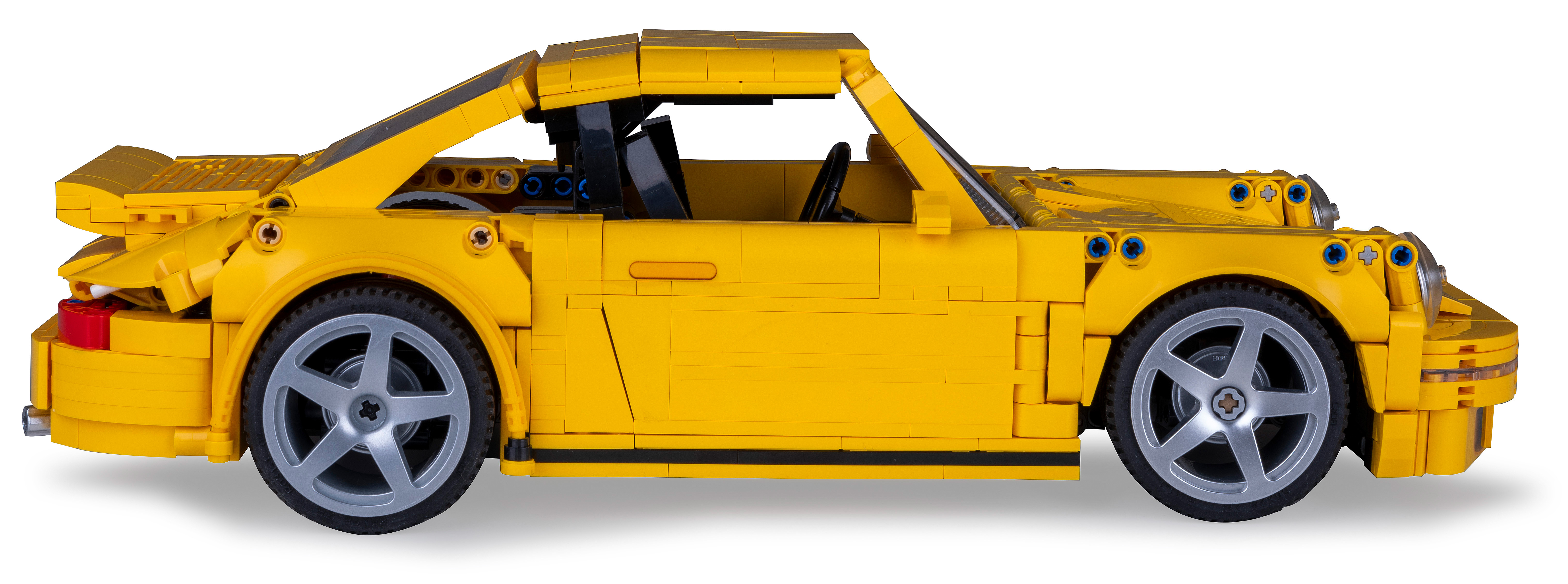 Ein gelbes Spielzeugauto, von der Seite vor einem weißen Hintergrund fotografiert.