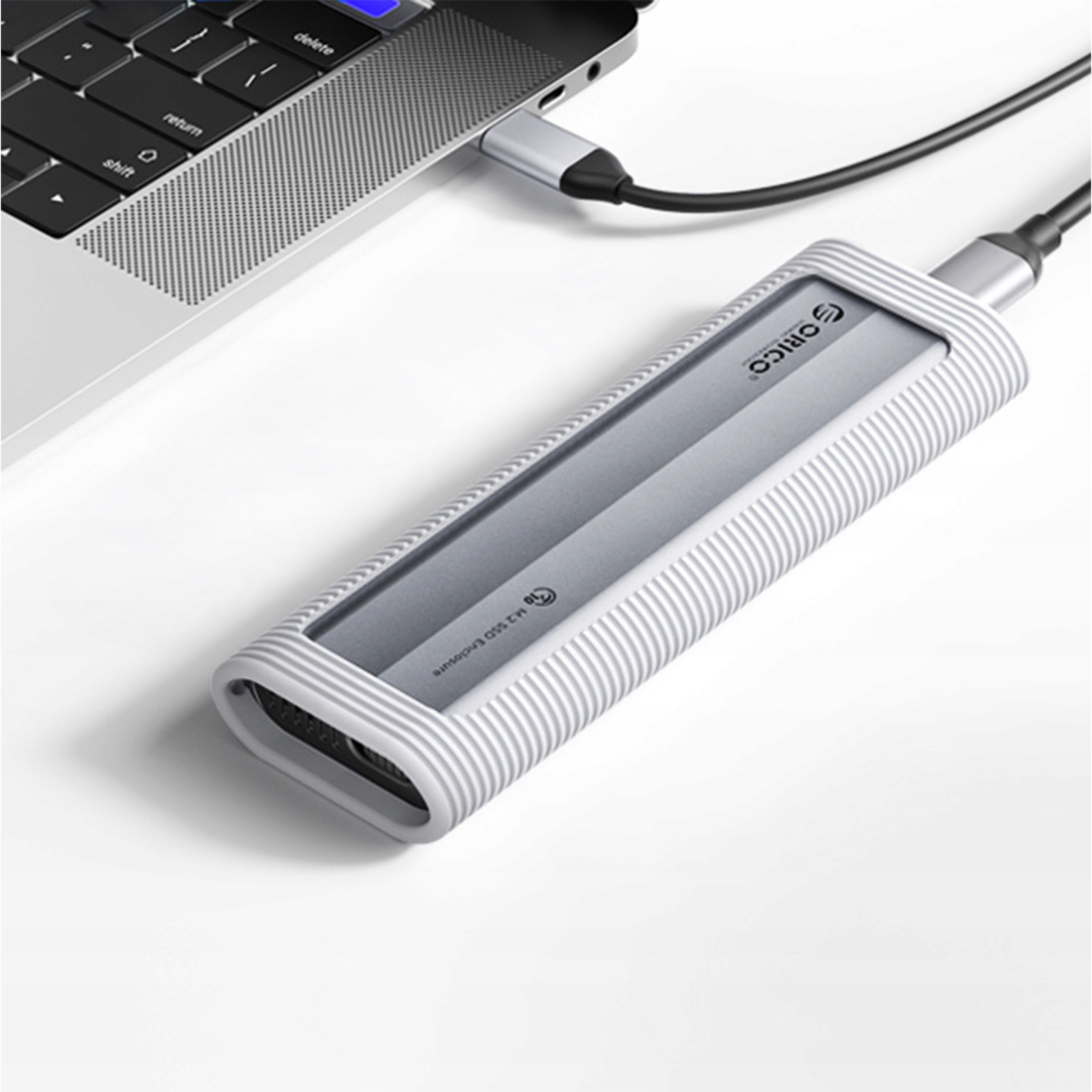 Zewnętrzny dysk SSD podłączony do laptopa. Obudowa jest srebrna i biała.