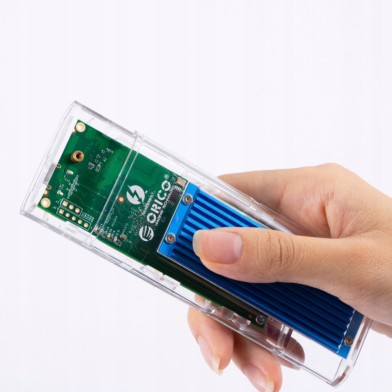 Dłoń trzymająca przezroczystą obudowę z niebieskim metalowym elementem w środku. Widok z boku.