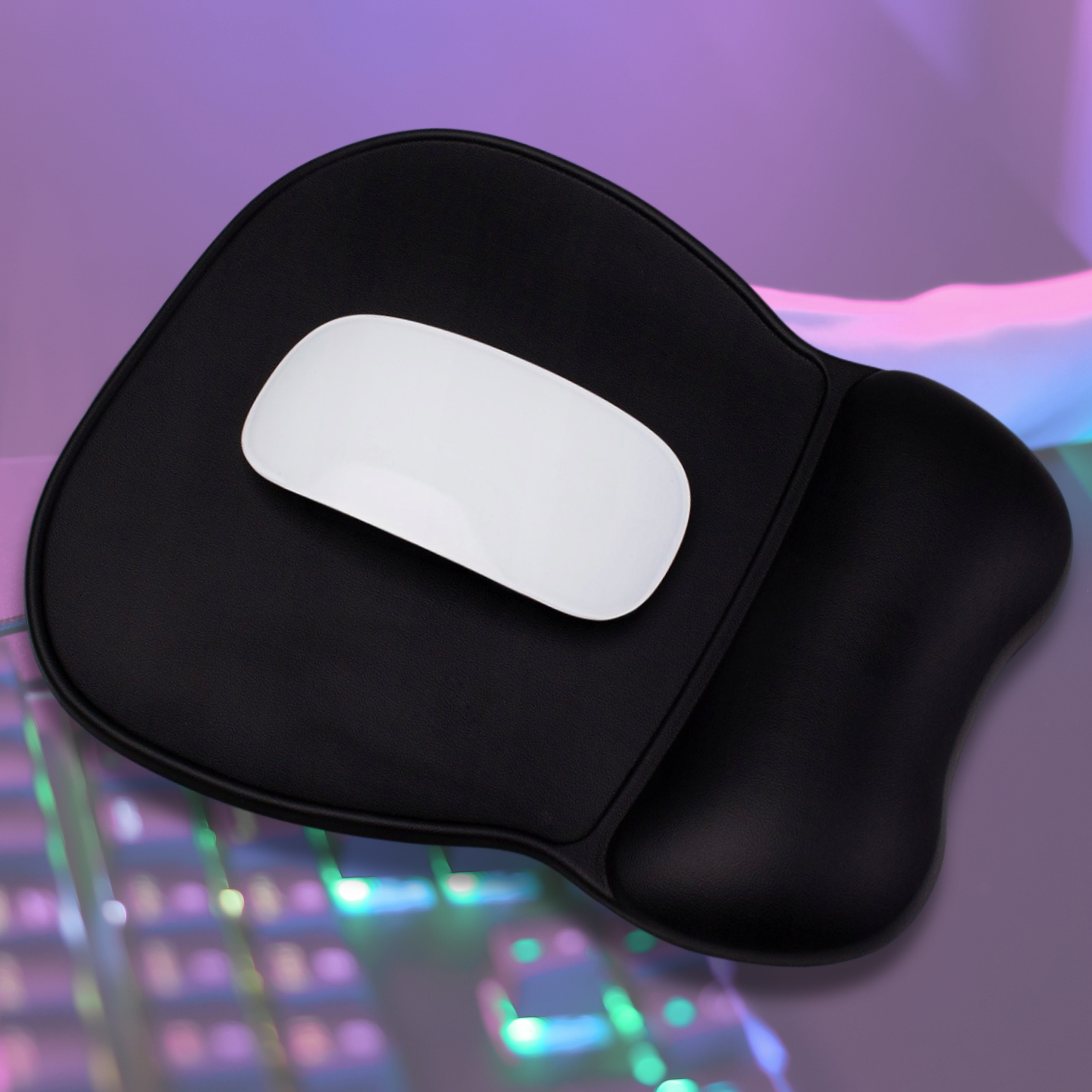 Czarna podkładka pod mysz z białą myszą na wierzchu. Tło to biurko z klawiaturą.