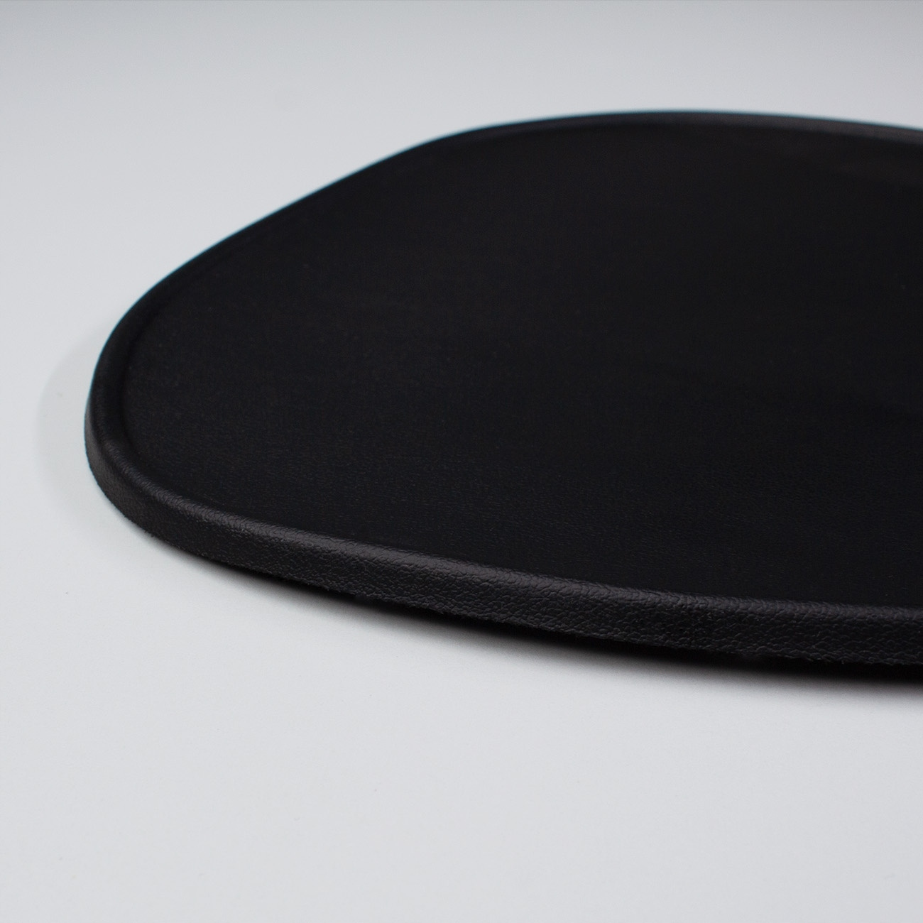 Zbliżenie czarnej podkładki pod mysz. Podkładka jest w jednolitym czarnym kolorze z lekko teksturowaną powierzchnią.