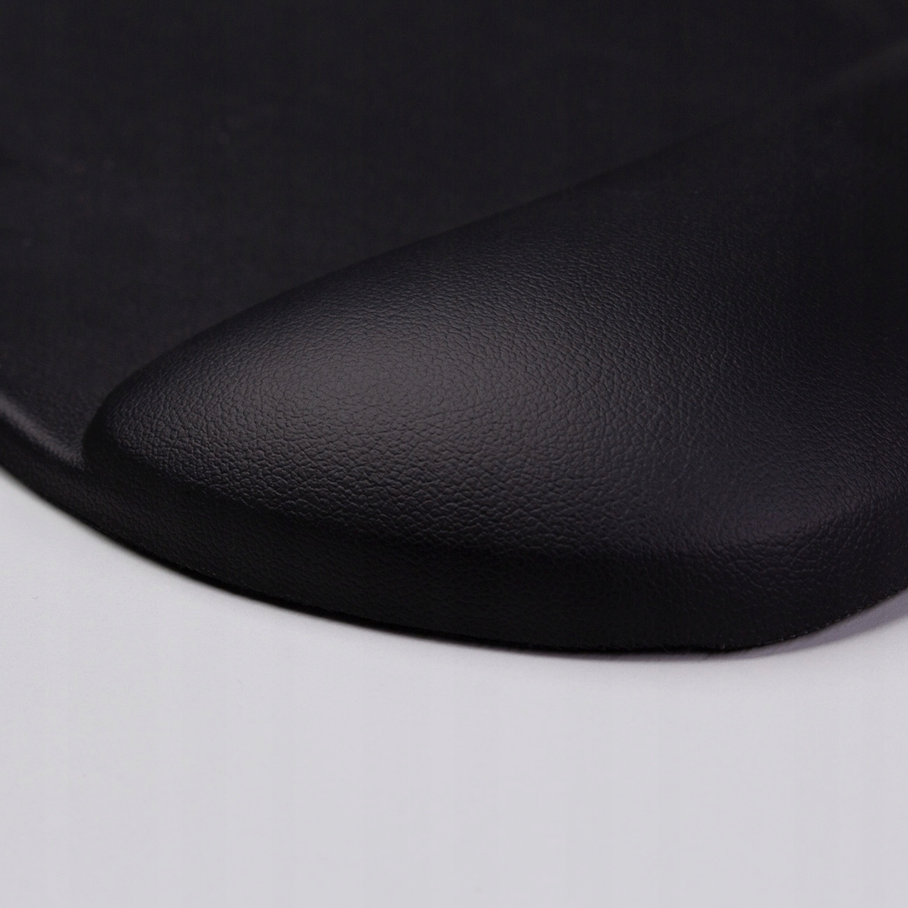 Zbliżenie czarnej, ergonomicznej podkładki pod mysz z podpórką pod nadgarstek, na białym tle.