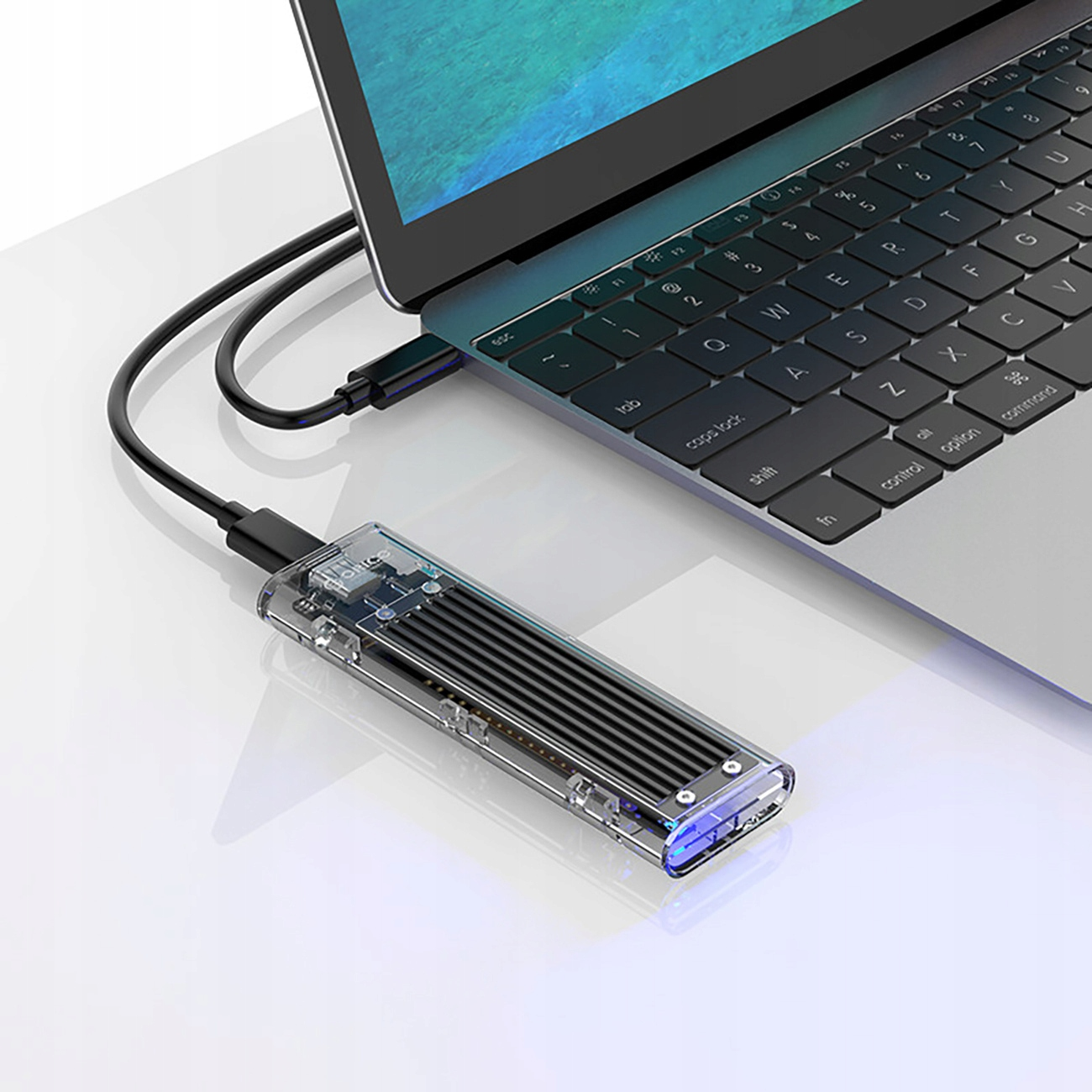 Laptop z podłączonym zewnętrznym dyskiem SSD. Dysk SSD jest przezroczysty, kabel podłączony do laptopa.