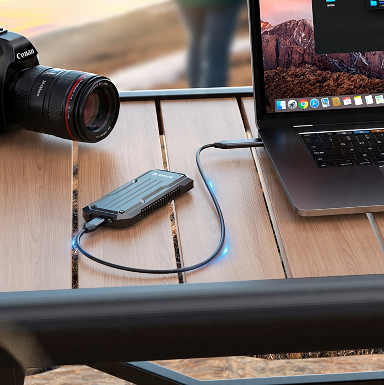 Czarny zewnętrzny dysk SSD podłączony do laptopa na drewnianym stole.