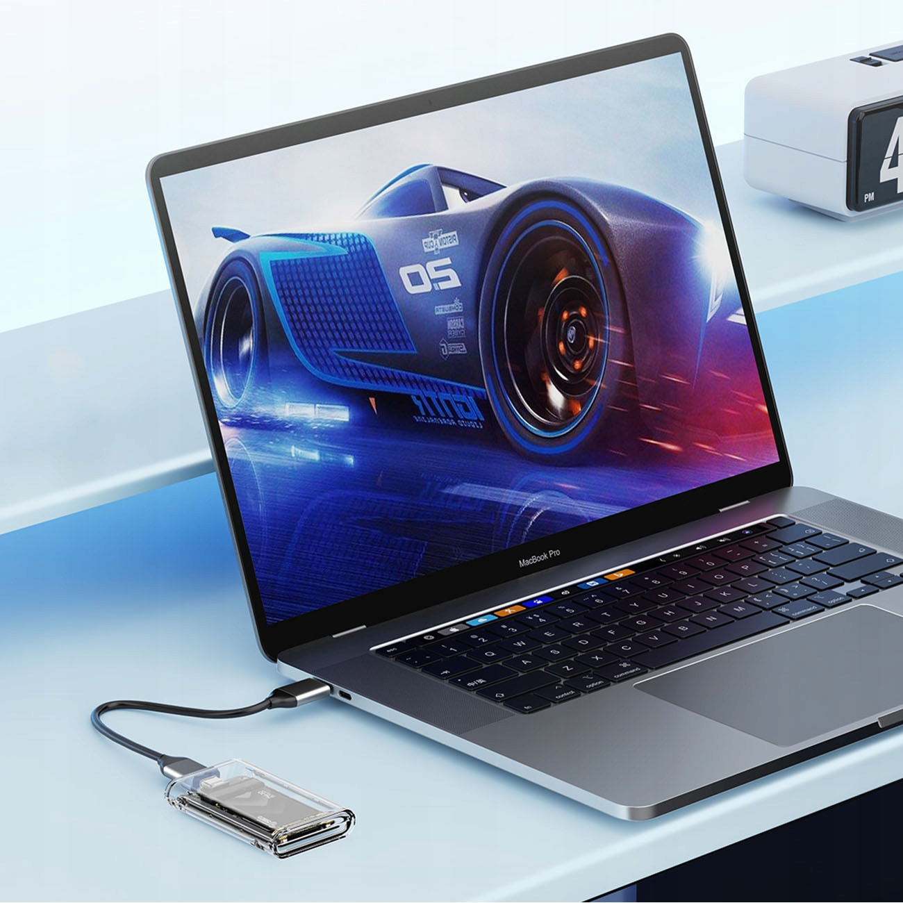 Ekran laptopa pokazuje obraz z filmu Auta, z podłączonym dyskiem SSD w przezroczystej obudowie.