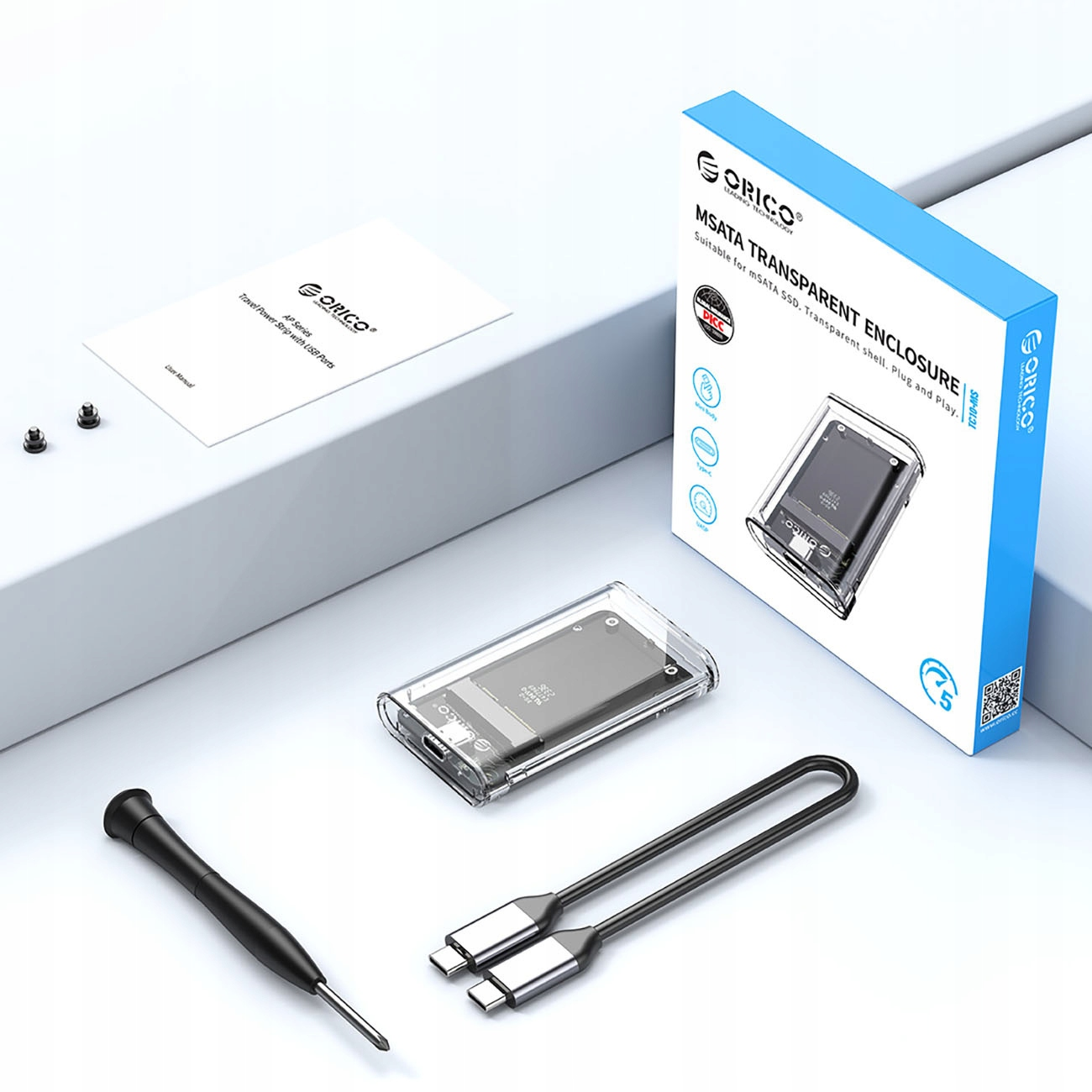 Zdjęcie produktu z przezroczystą obudową, pudełkiem, śrubokrętem i akcesoriami na powierzchni.