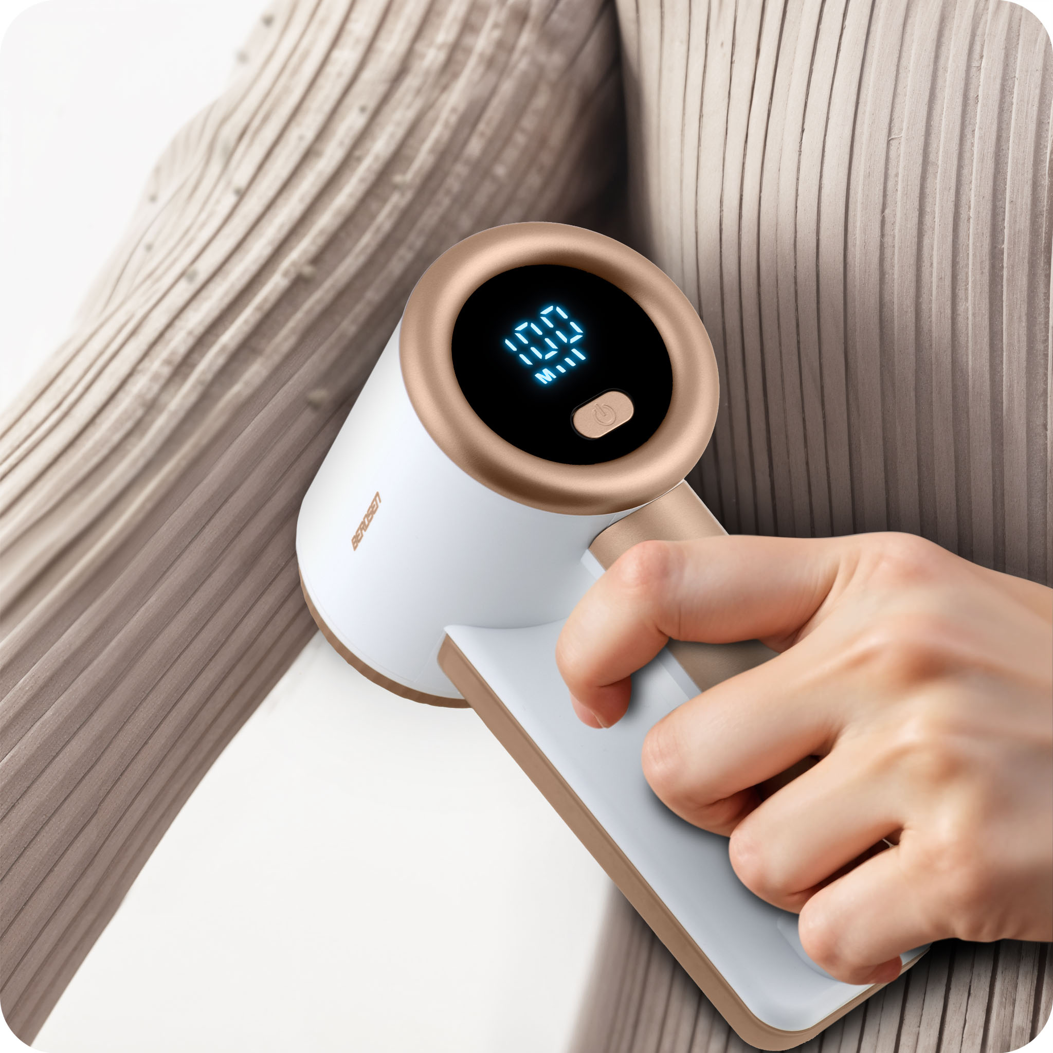 Kobieta używa golarki do tkanin, aby usunąć kłaczki z swetra.