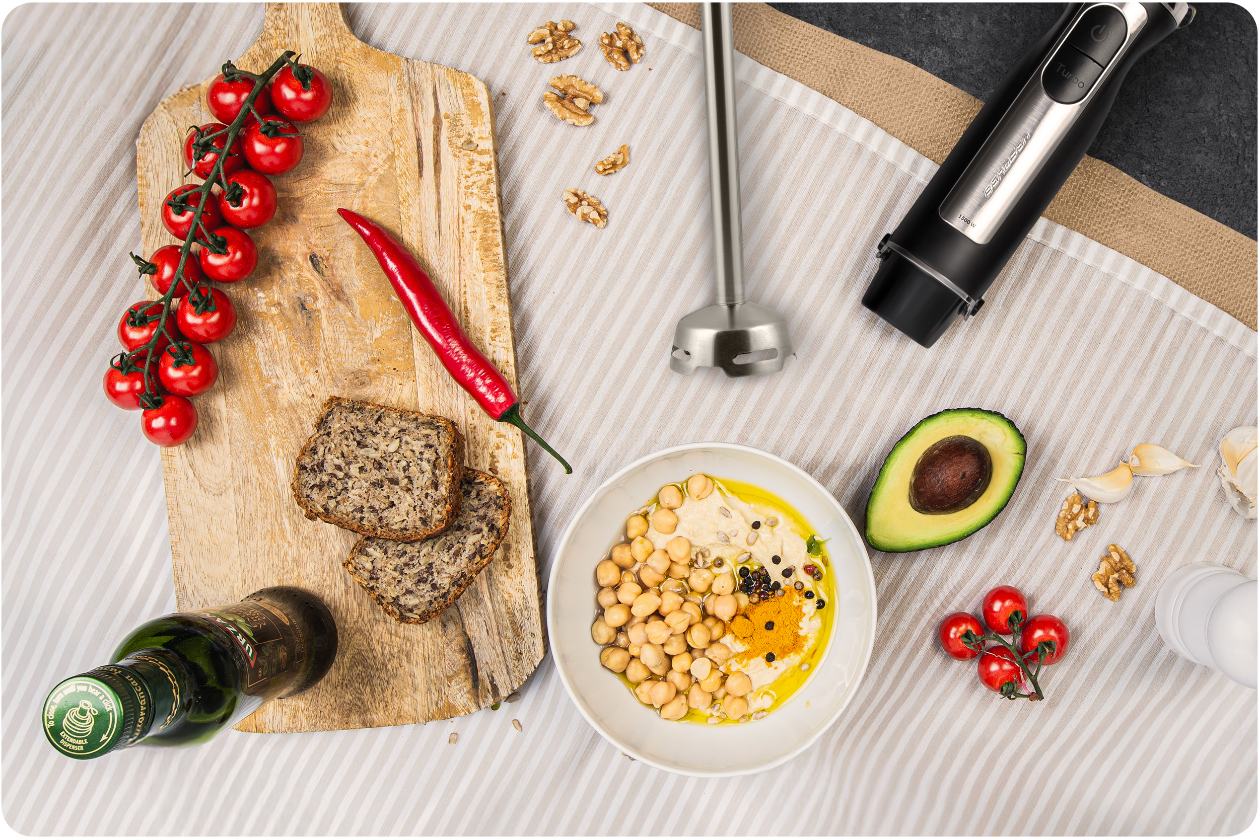 Składniki na desce: pomidory, chili, chleb, hummus, awokado i blender.