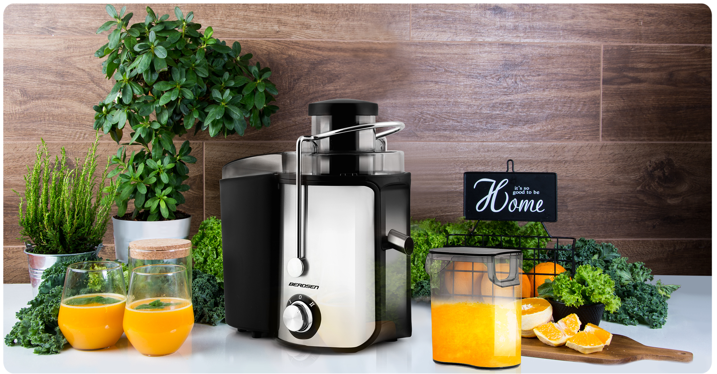Wyciskarka do soku jest prezentowana na stole ze szklankami soku, pomarańczami i roślinami, tworząc żywą scenę.