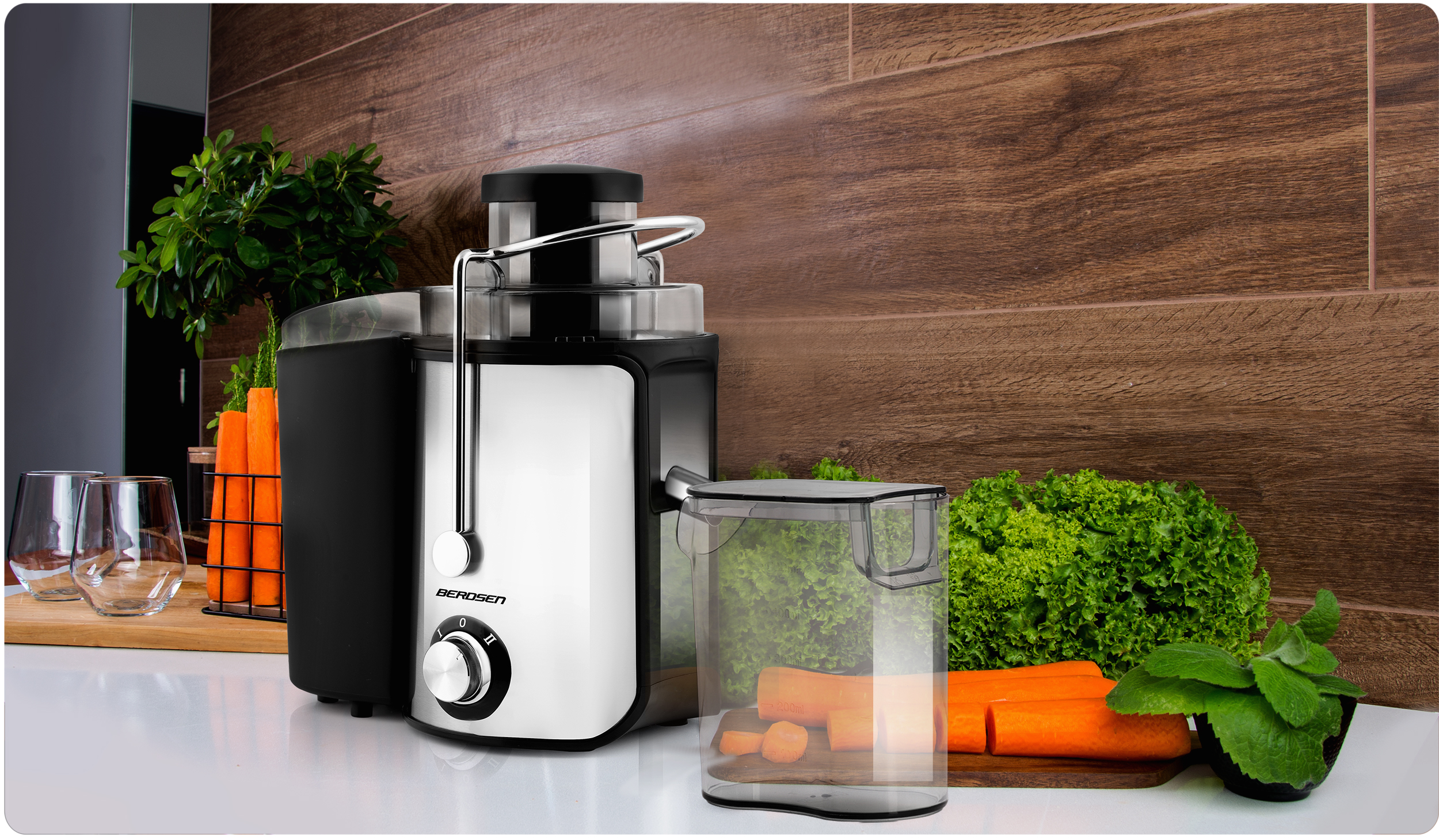 Wyżymacz do owoców w otoczeniu kuchennym, z widoczną marchewką i innymi składnikami. Scena ma drewniane tło i białe powierzchnie.