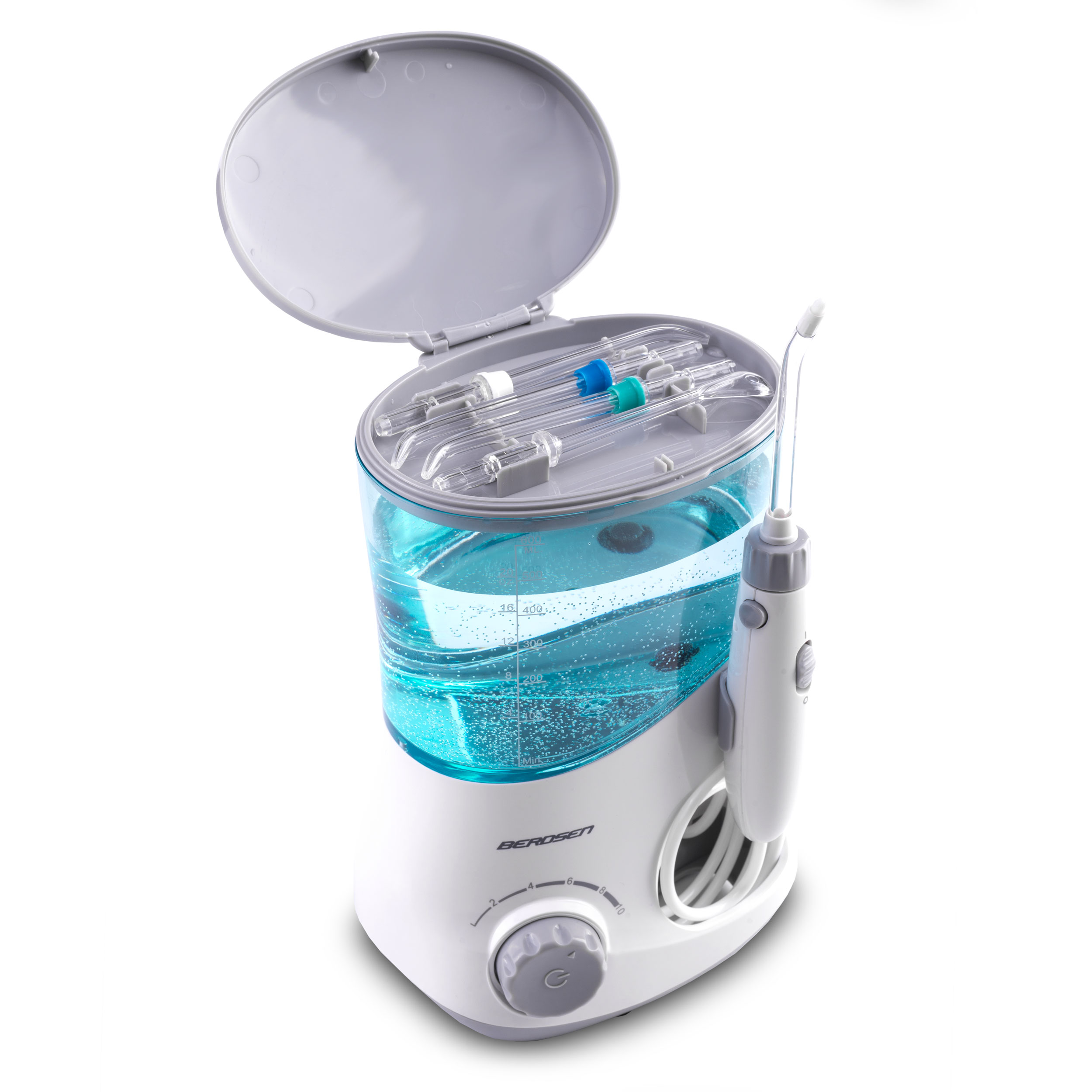 Biały irygator z zbiornikiem na wodę wypełnionym niebieskim płynem. Urządzenie jest otwarte, akcesoria widoczne.